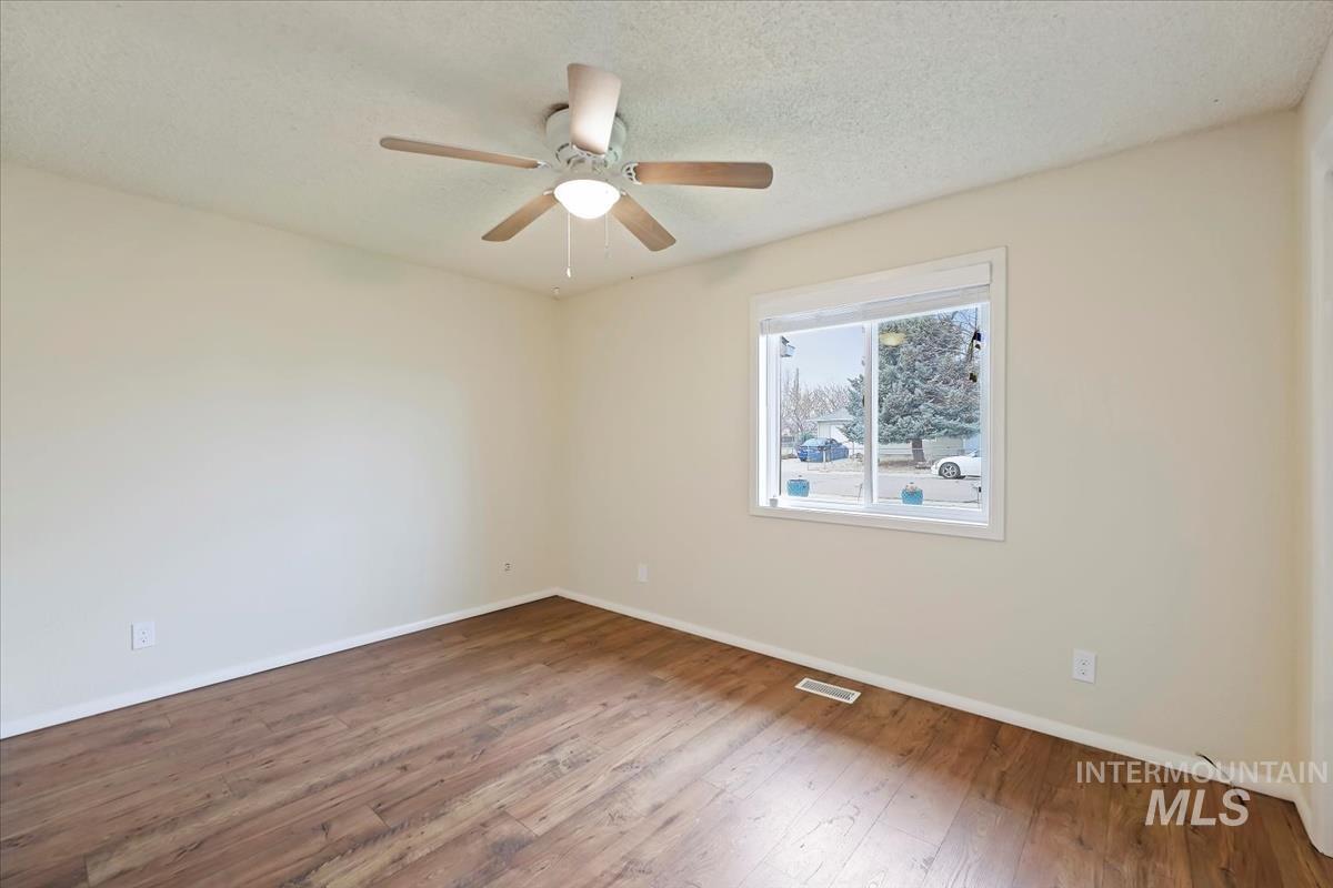 Empty room featuring wood-type flooring, a textured ceiling, and a ceiling fan