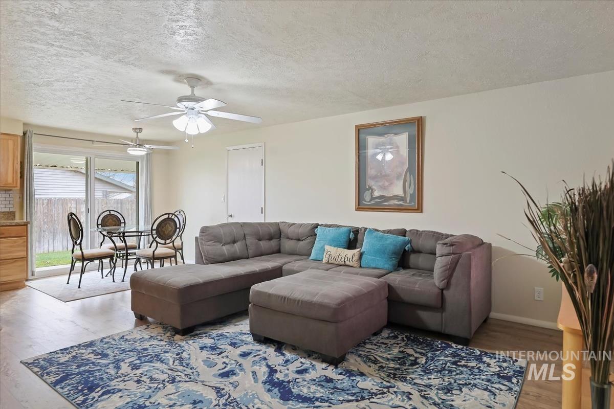 Living room with wood finished floors, a textured ceiling, and ceiling fan
