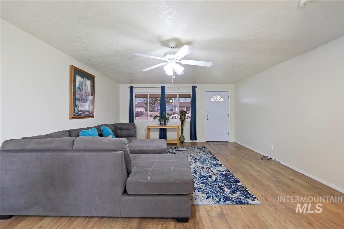 Living area featuring wood finished floors, a ceiling fan, and a textured ceiling