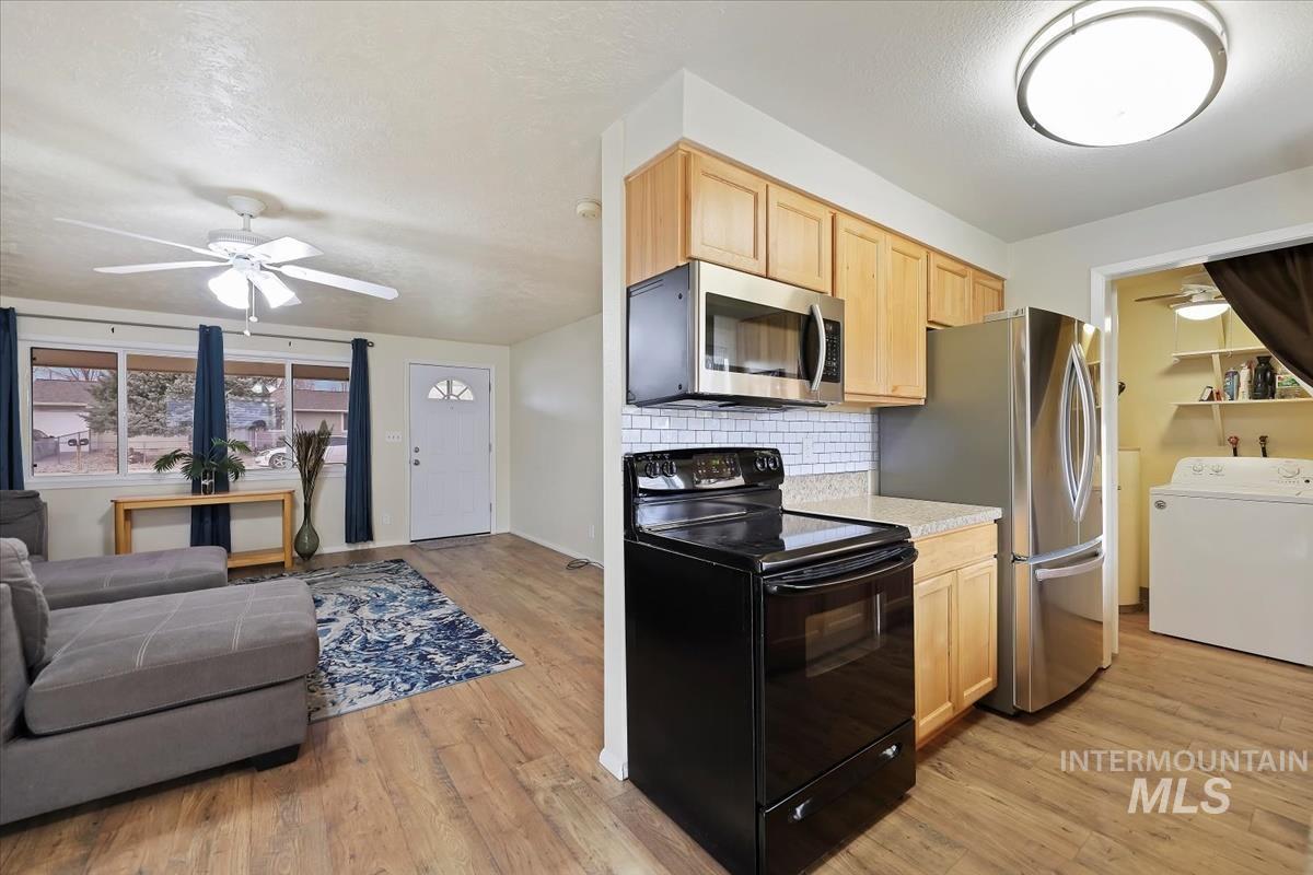 Kitchen featuring a ceiling fan, stainless steel appliances, light countertops, washer / clothes dryer, and light brown cabinets