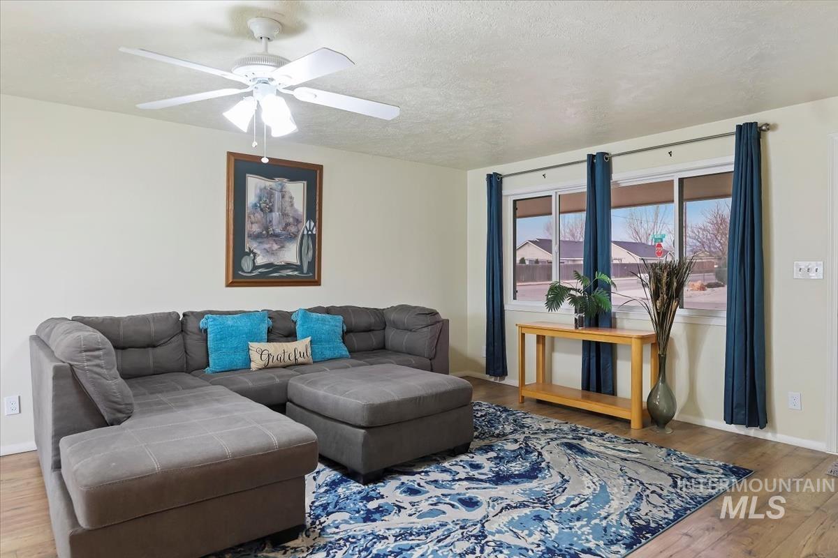 Living area with wood-type flooring, a textured ceiling, and ceiling fan