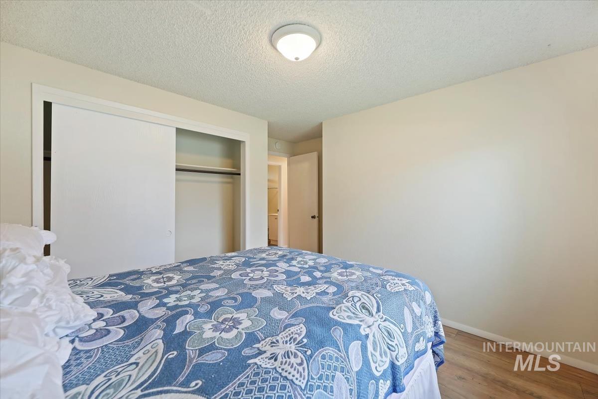 Bedroom featuring a textured ceiling, wood finished floors, and a closet