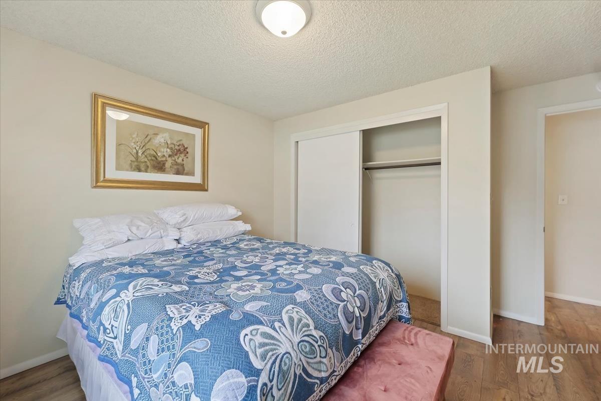 Bedroom featuring a textured ceiling, a closet, and wood finished floors