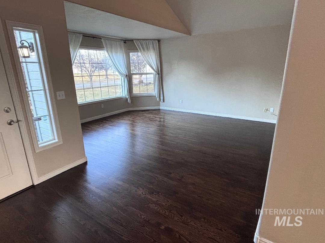 Spare room with dark wood-style floors and lofted ceiling