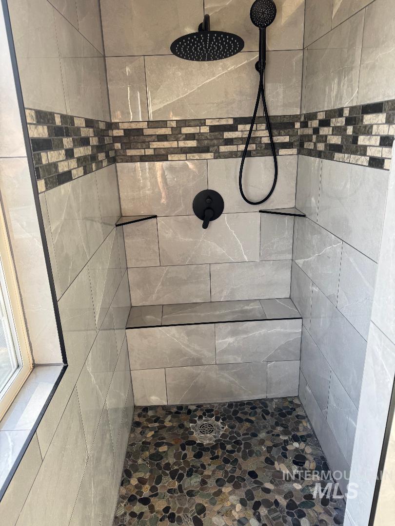 Full bath with a tile shower and stone finish floors