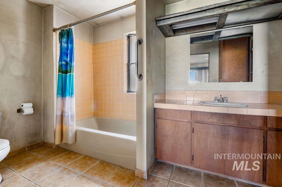 Full bathroom with tile patterned floors, vanity, and shower / tub combo