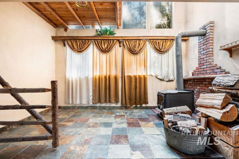 Interior space with stone tile floors, wooden ceiling, and a wood stove