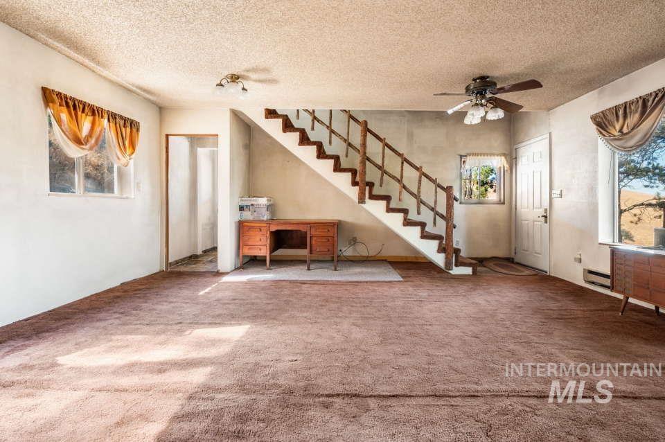 Foyer entrance with a textured ceiling, carpet floors, a ceiling fan, and stairway