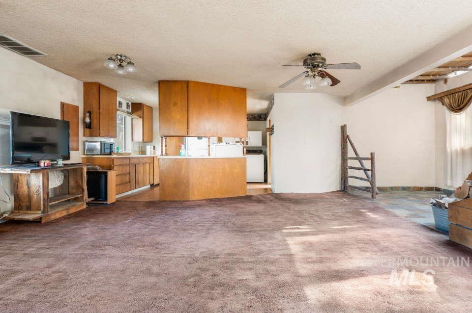 Kitchen featuring brown cabinets, a ceiling fan, carpet floors, a textured ceiling, and light countertops