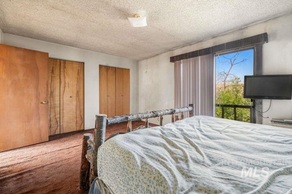 Carpeted bedroom with a textured ceiling and multiple closets