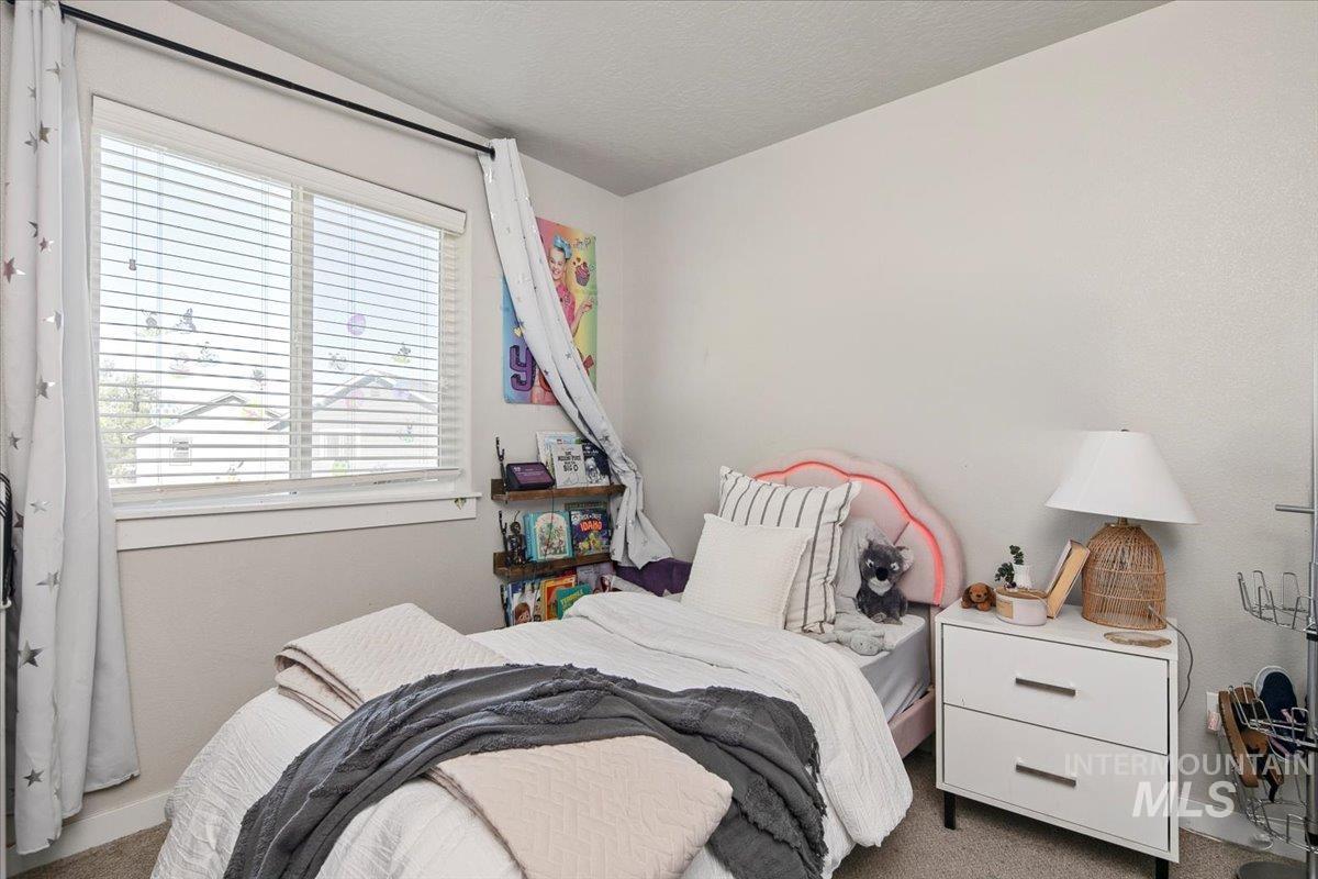 Carpeted bedroom featuring baseboards and a textured ceiling