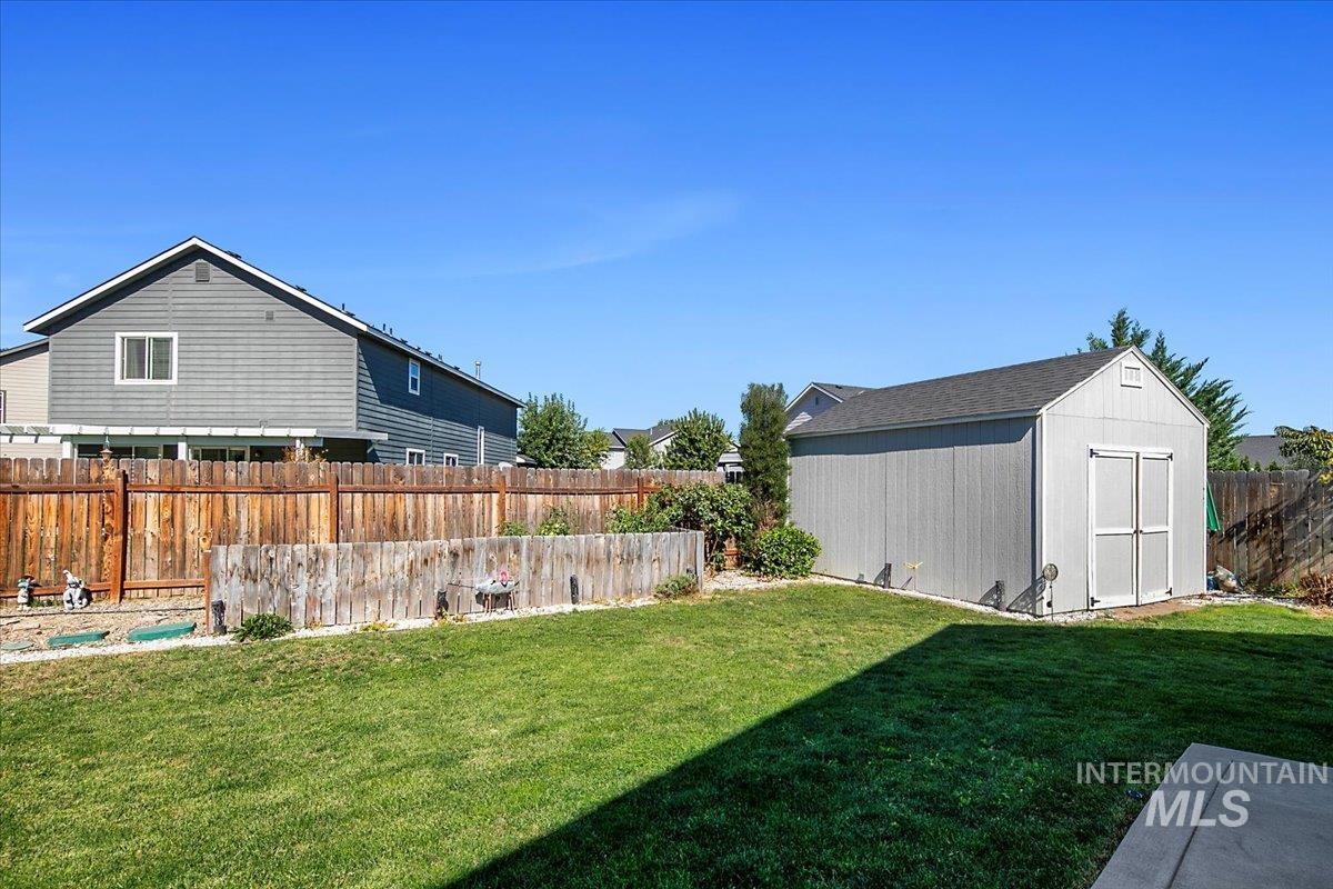 Fenced backyard featuring a shed