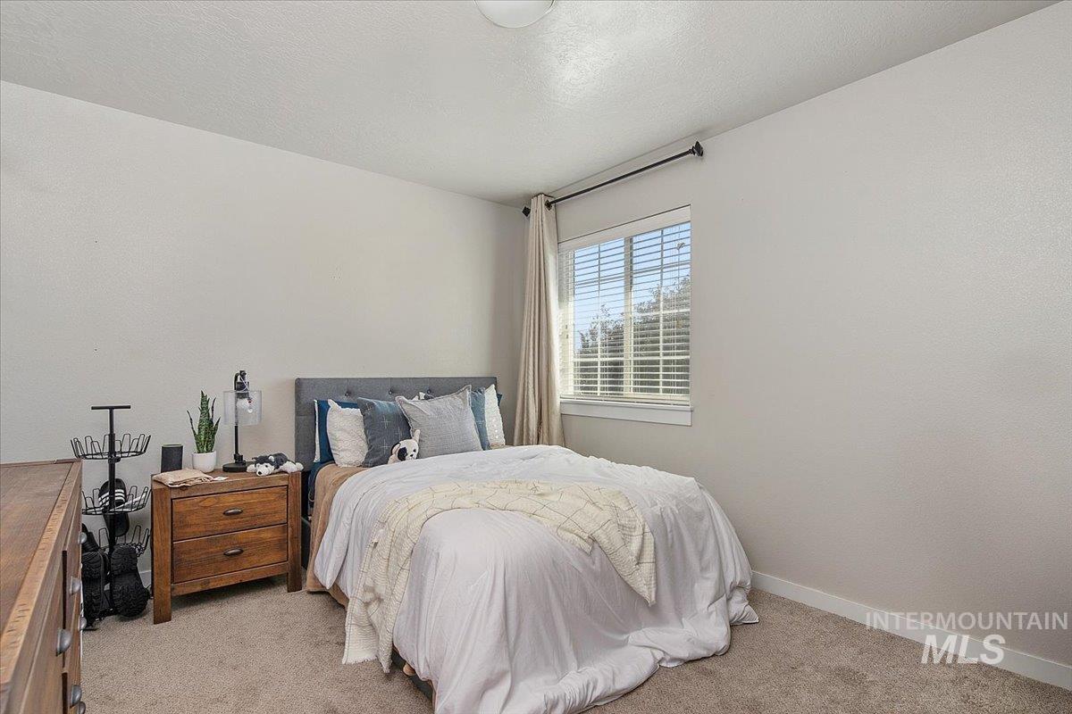 Bedroom featuring light colored carpet and a textured ceiling