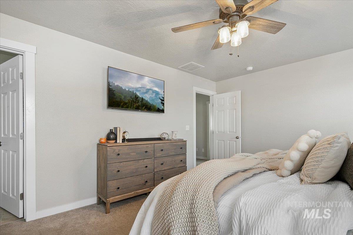 Carpeted bedroom with a textured ceiling and a ceiling fan