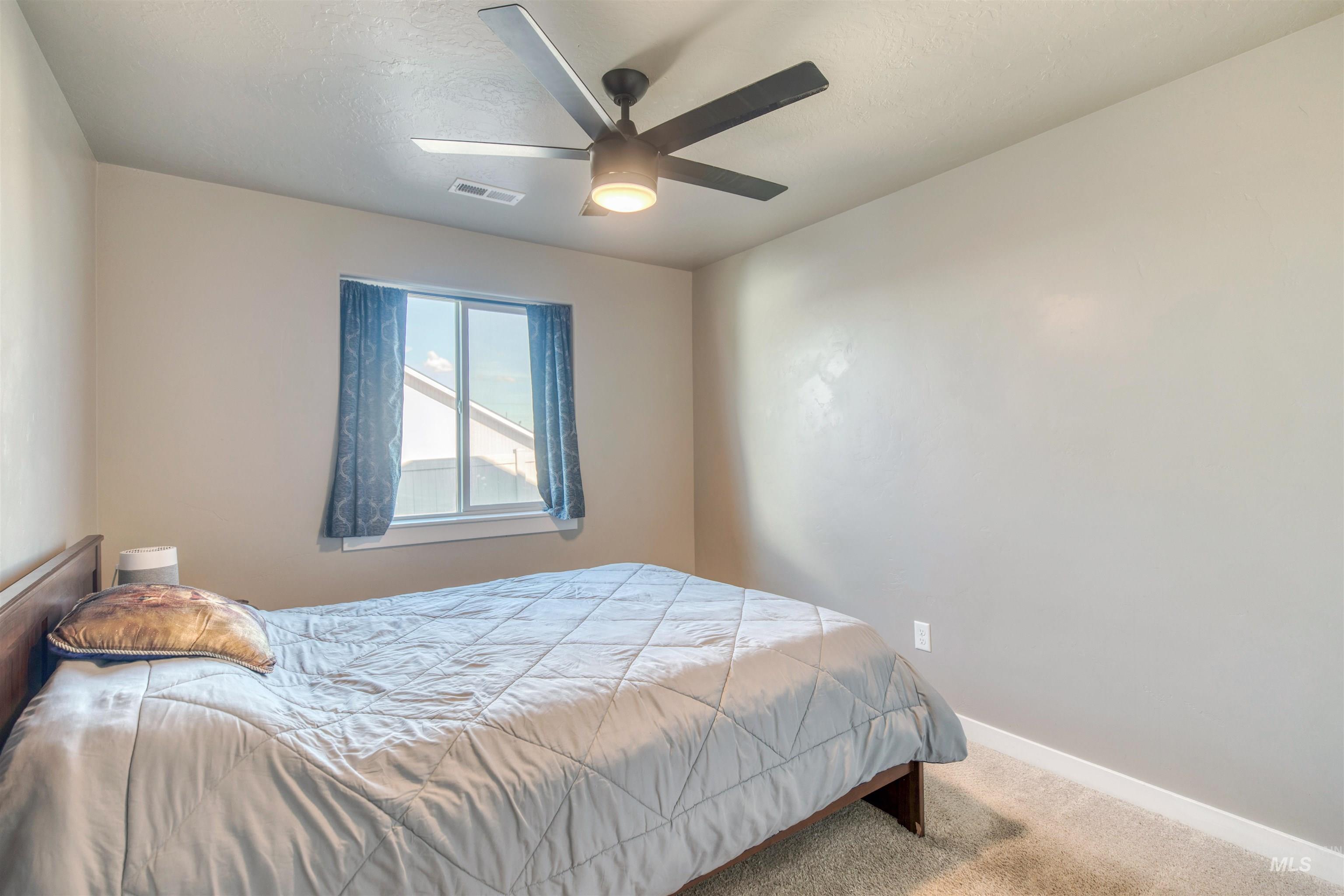 Carpeted bedroom featuring baseboards and a ceiling fan