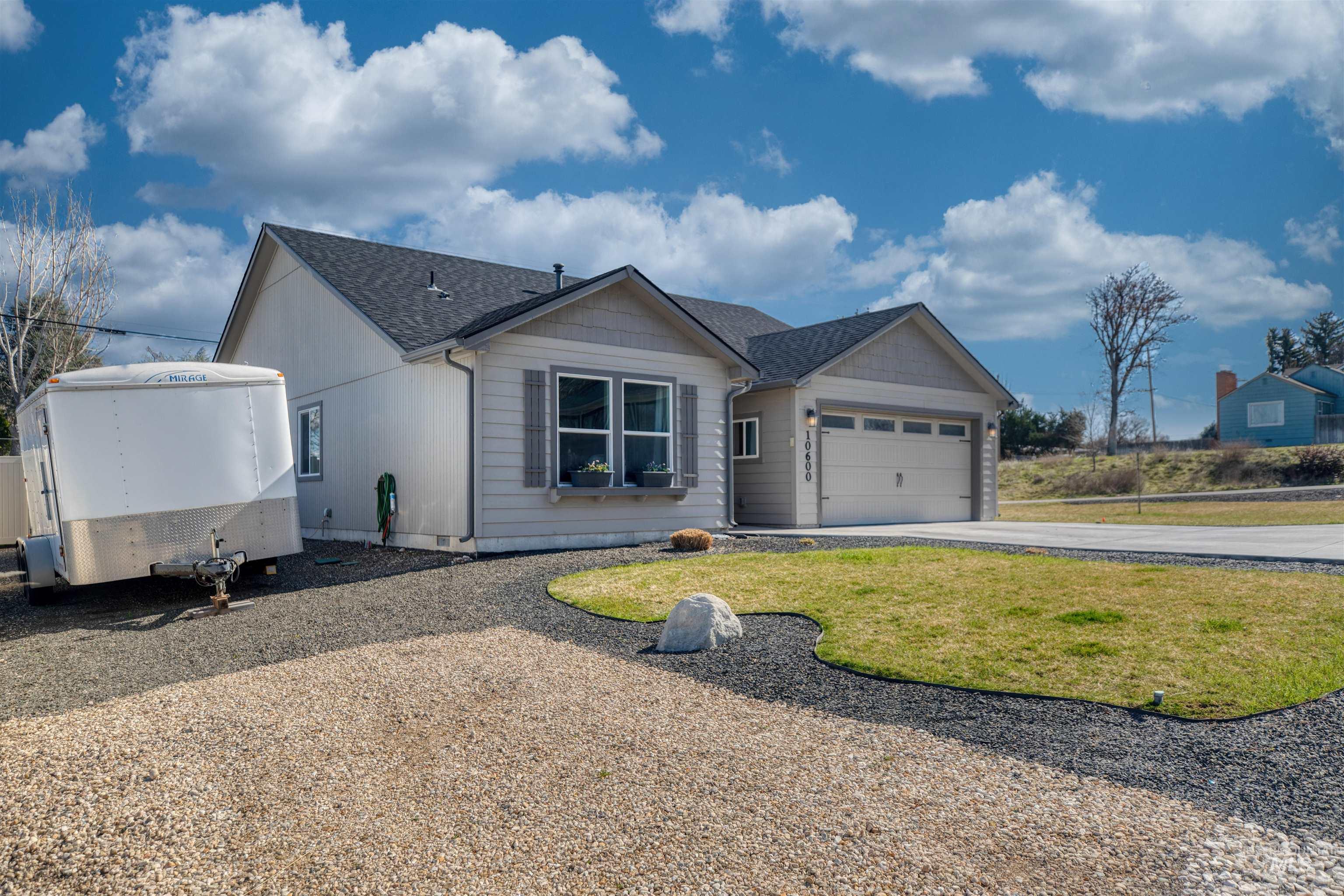 Single story home featuring driveway, an attached garage, roof with shingles, and a front lawn