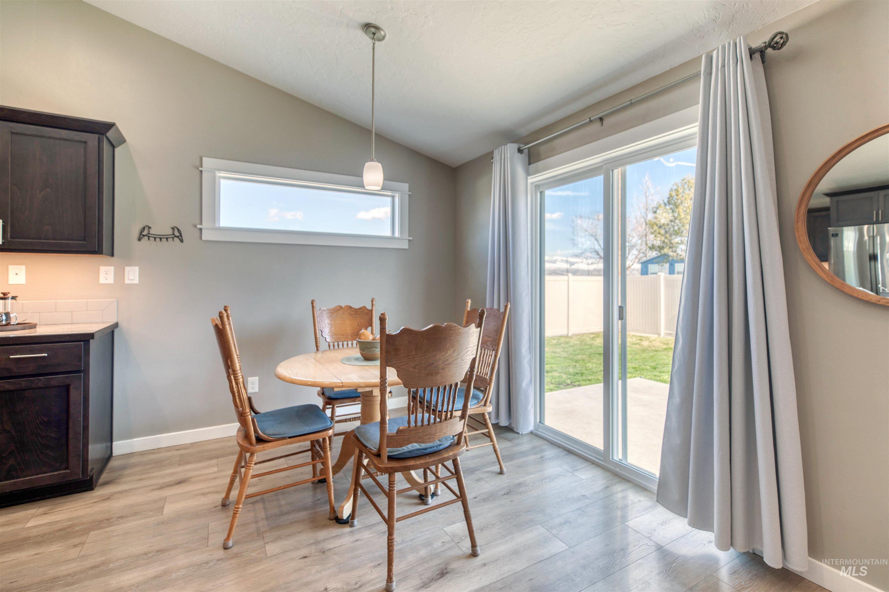 Dining space with vaulted ceiling and light wood-type flooring
