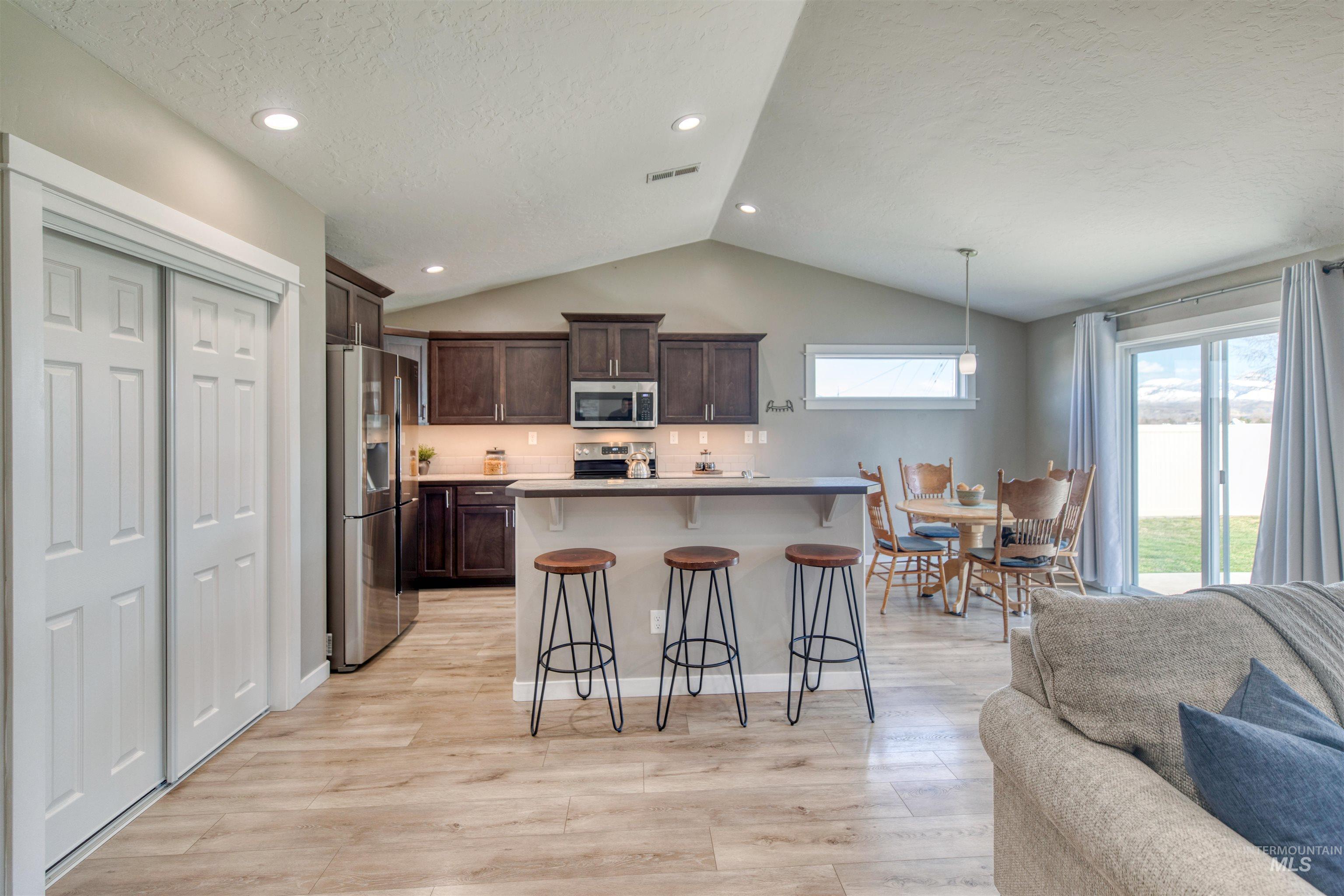 Kitchen with a kitchen bar, open floor plan, dark wood finish cabinetry, stainless steel appliances, and light countertops