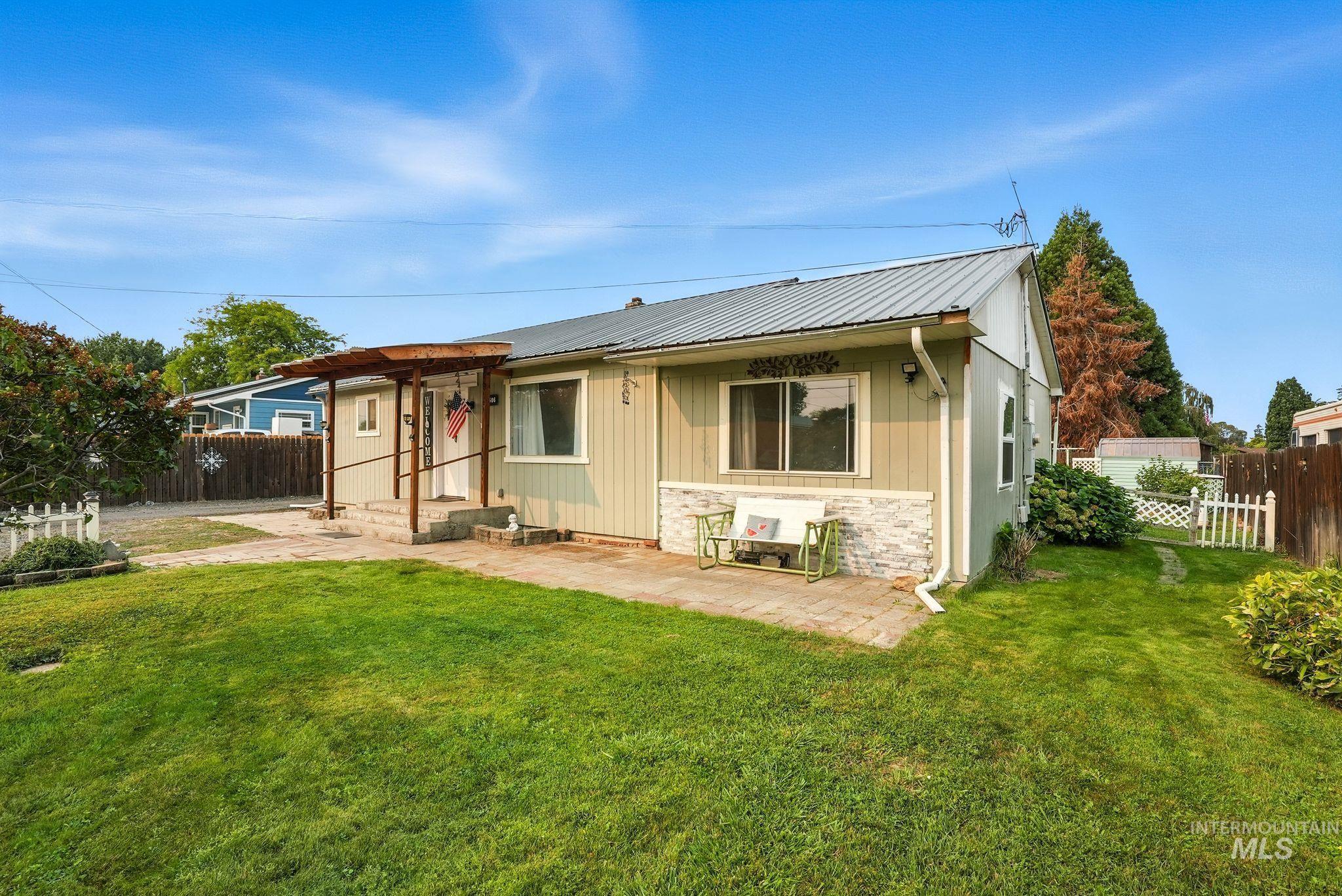 View of front of property with a patio, board and batten siding, a metal roof, and stone siding