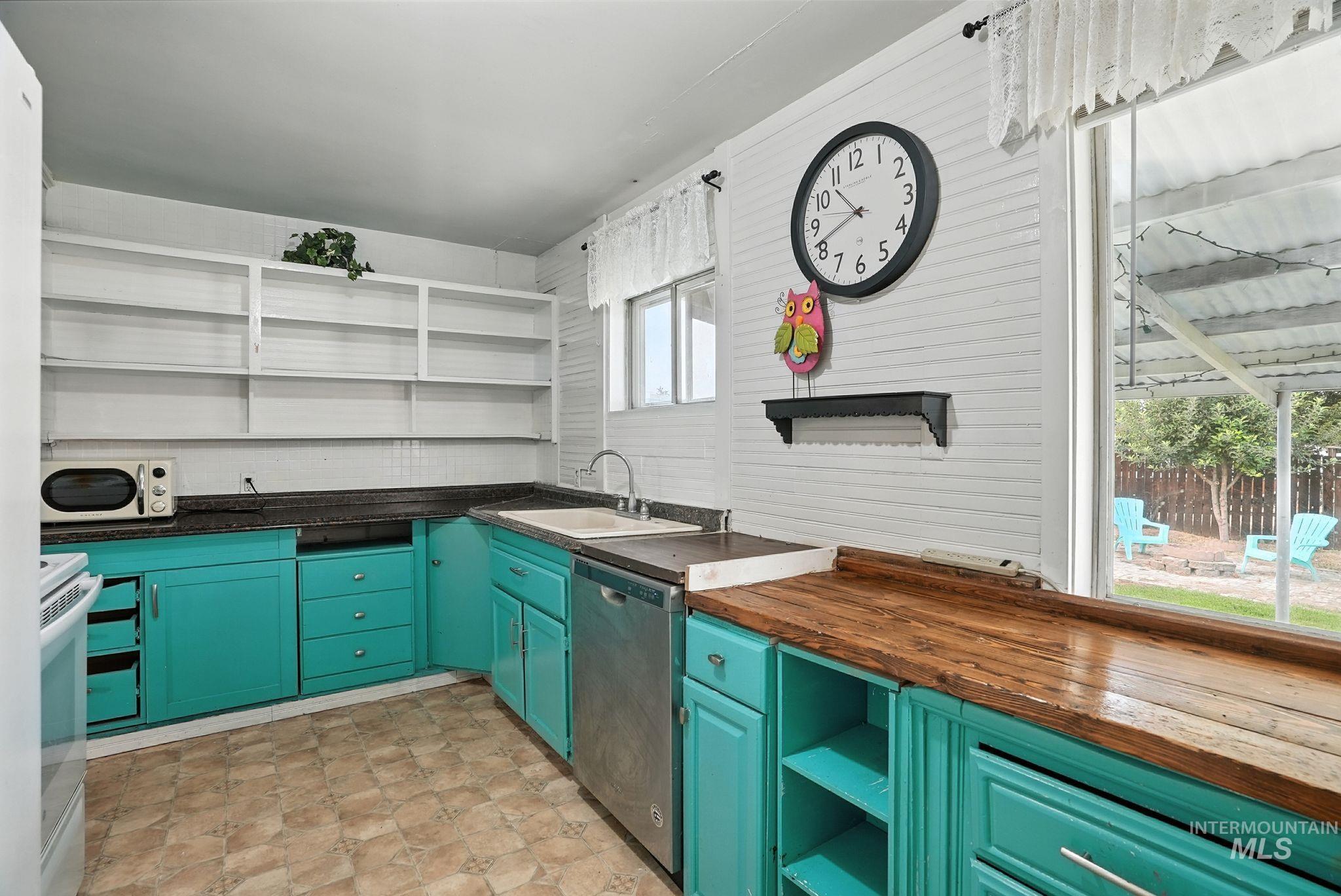 Kitchen featuring open shelves, stainless steel dishwasher, white range with electric stovetop, wood counters, and green cabinets