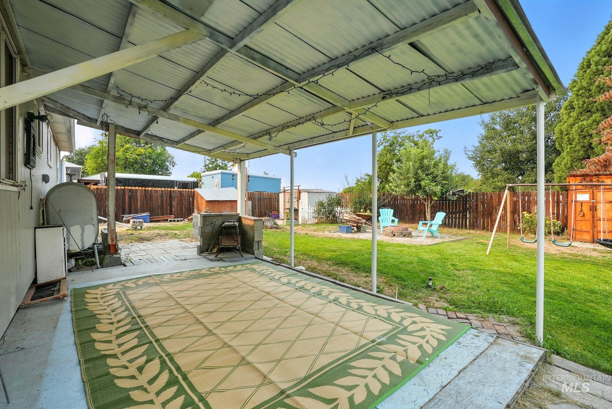 Fenced backyard with a patio area, a fire pit, a playground, and heating fuel