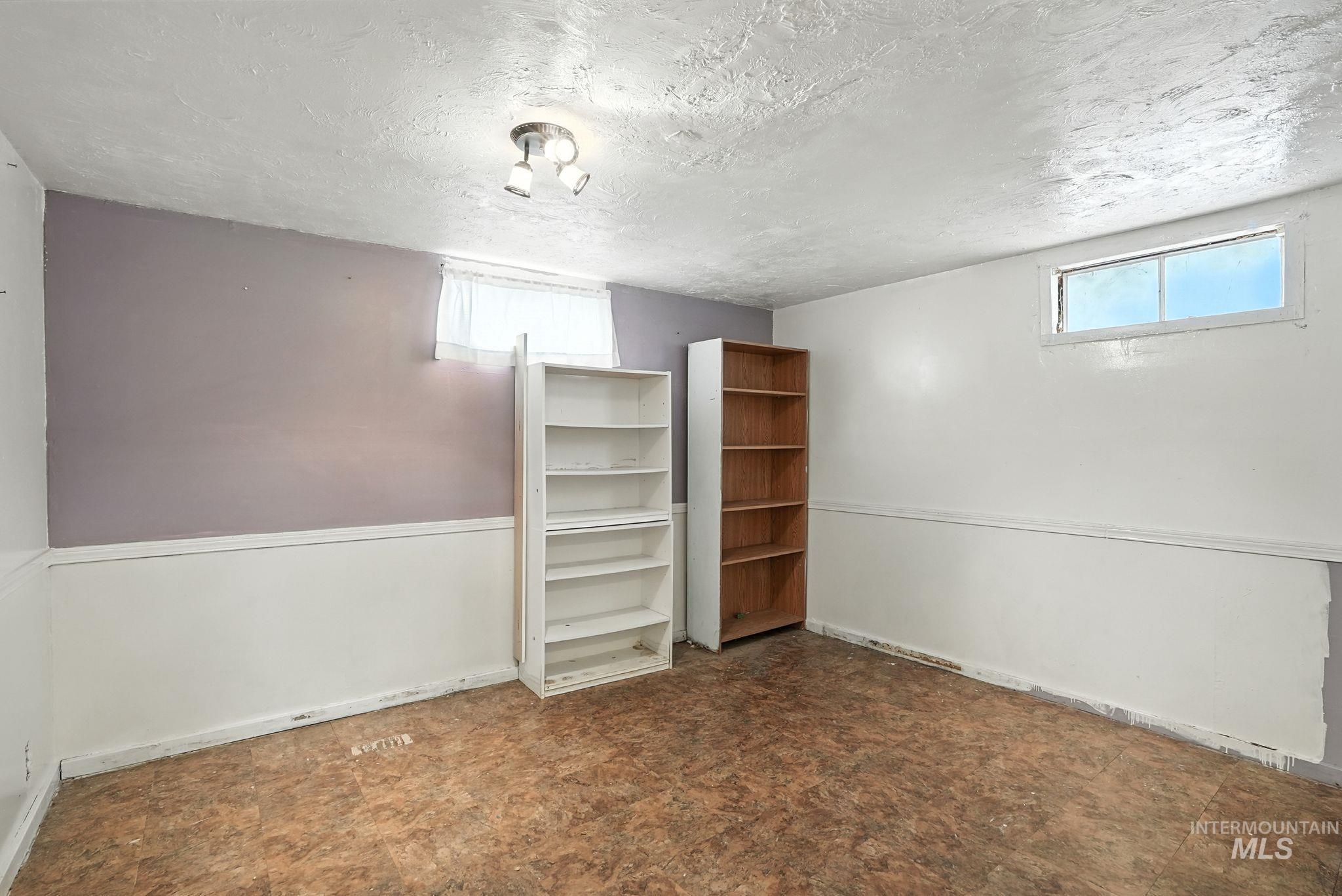 Basement with a textured ceiling and baseboards