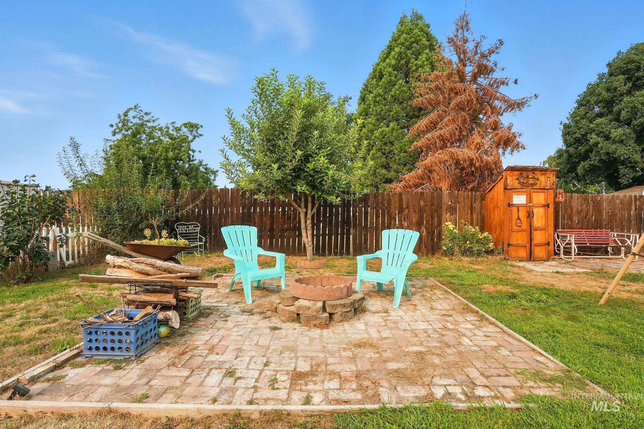 Fenced backyard with a patio, a fire pit, and a shed
