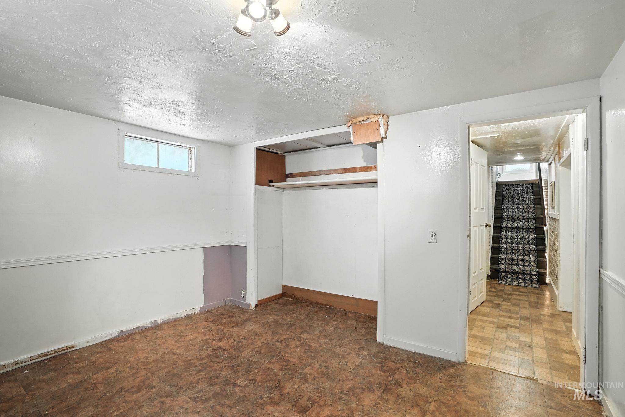 Basement featuring a textured ceiling and baseboards