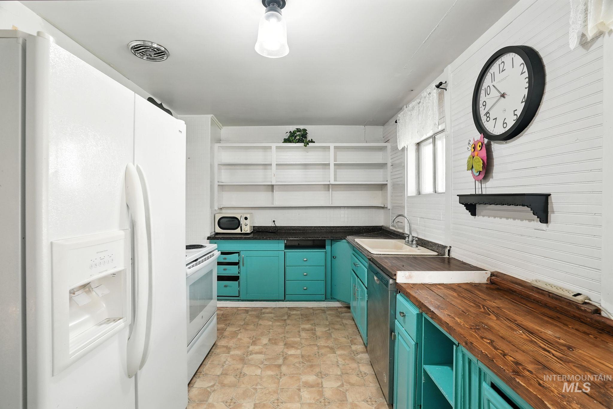 Kitchen featuring open shelves, white appliances, butcher block counters, and green cabinets