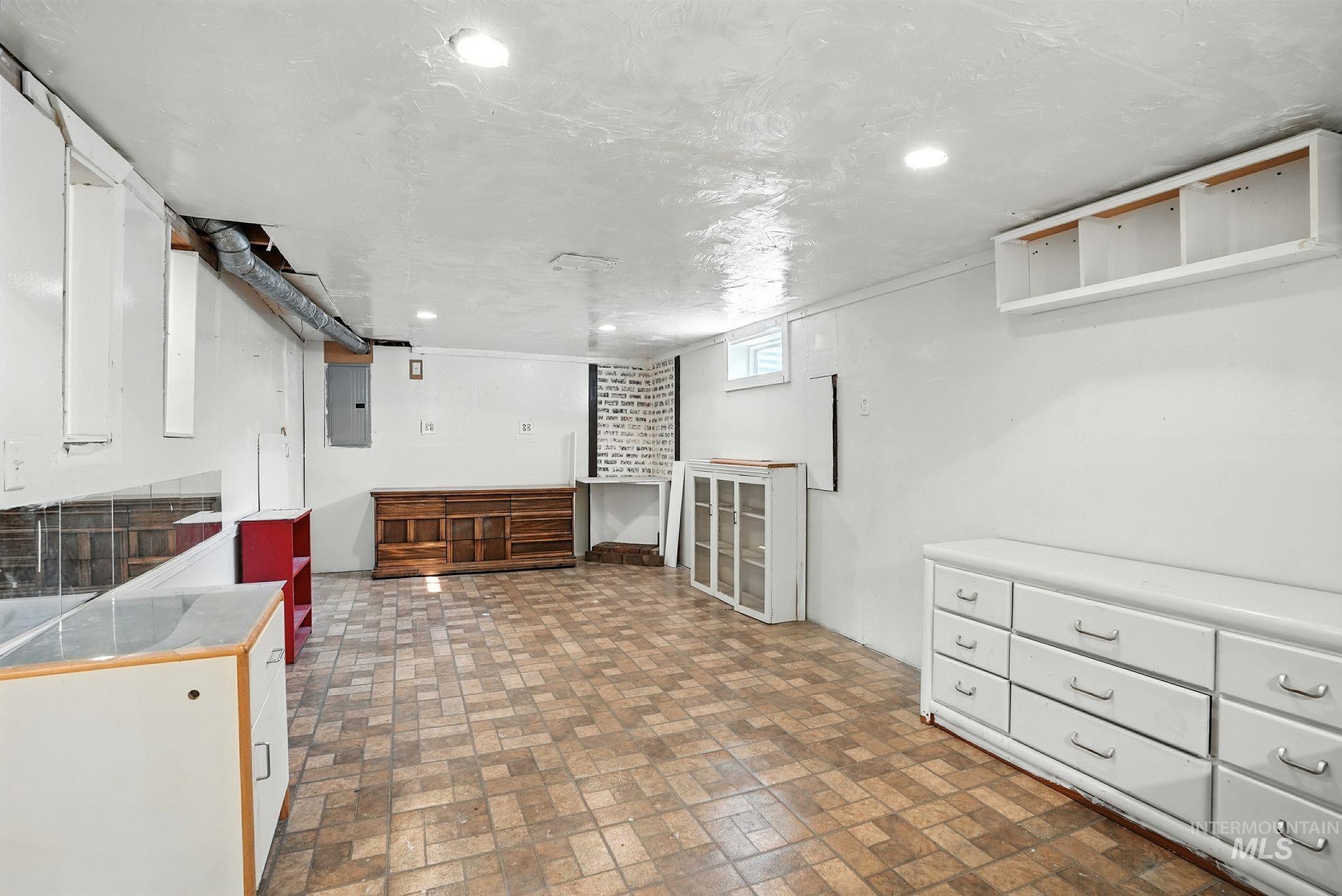 Basement featuring brick patterned flooring, electric panel, and recessed lighting