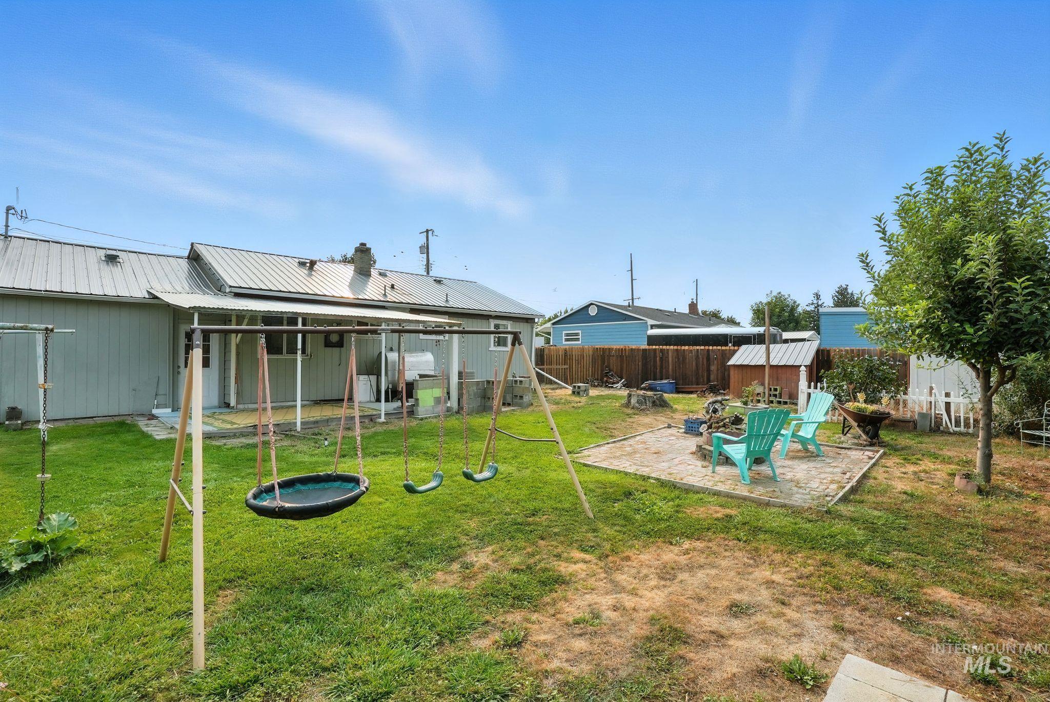 Fenced backyard featuring a patio area, a playground, and a storage shed