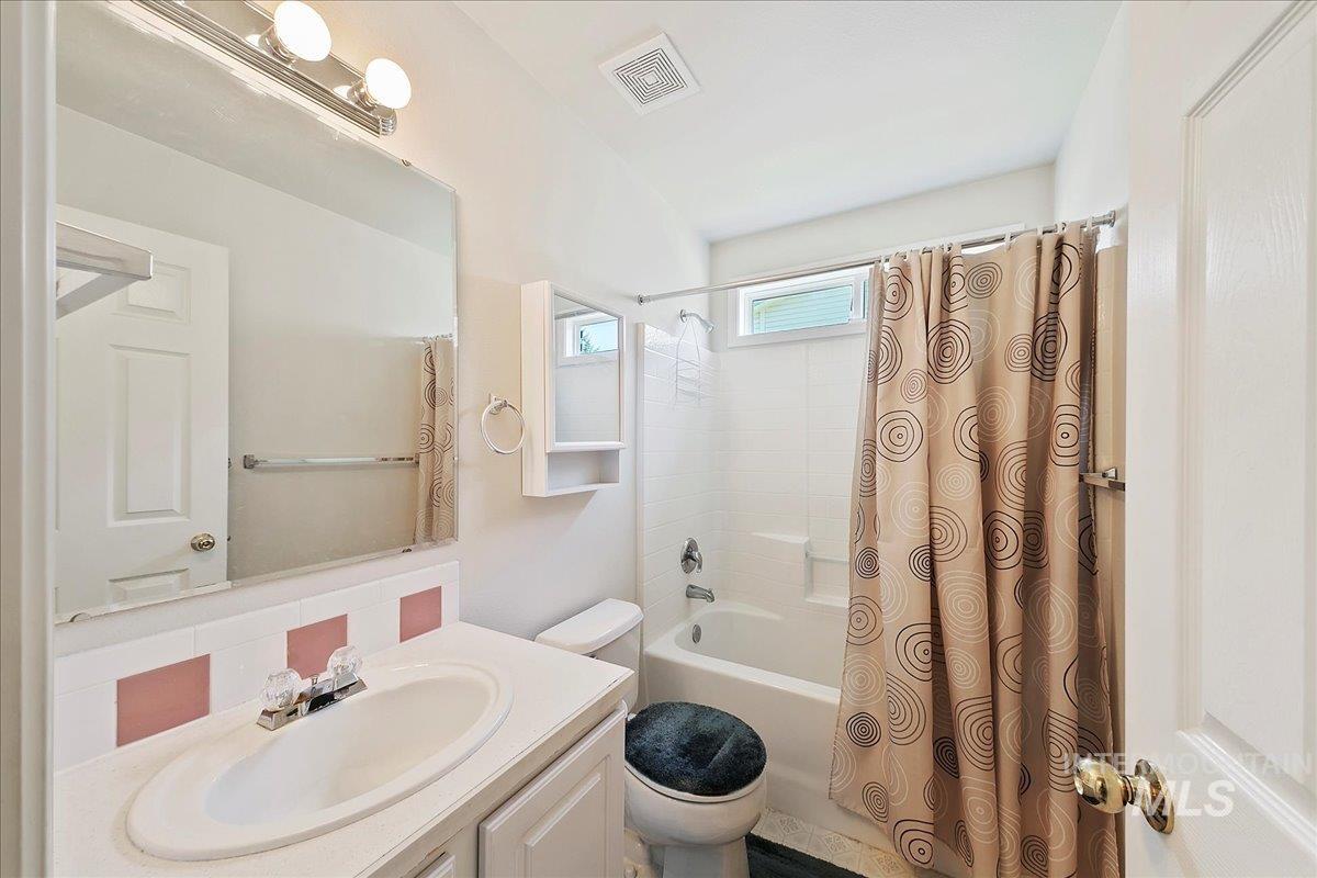 Bathroom with vanity, shower / bath combo, and backsplash
