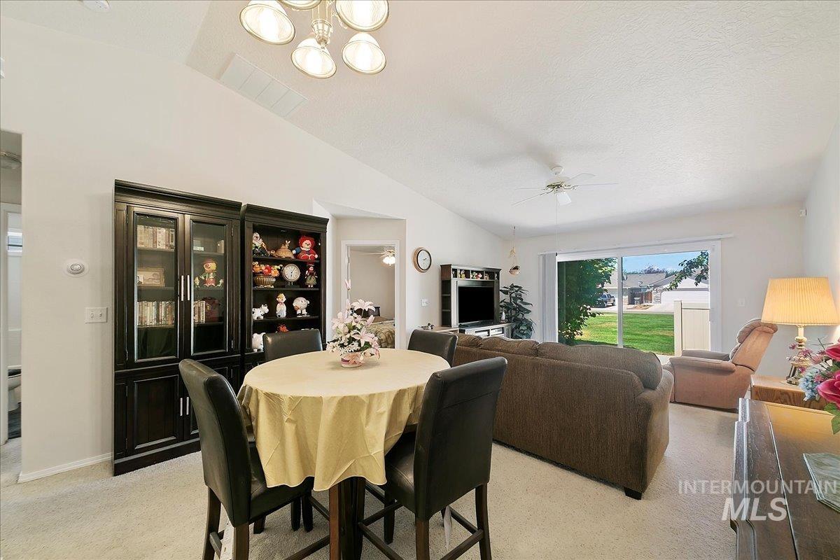 Dining space featuring lofted ceiling, light colored carpet, ceiling fan, and a chandelier