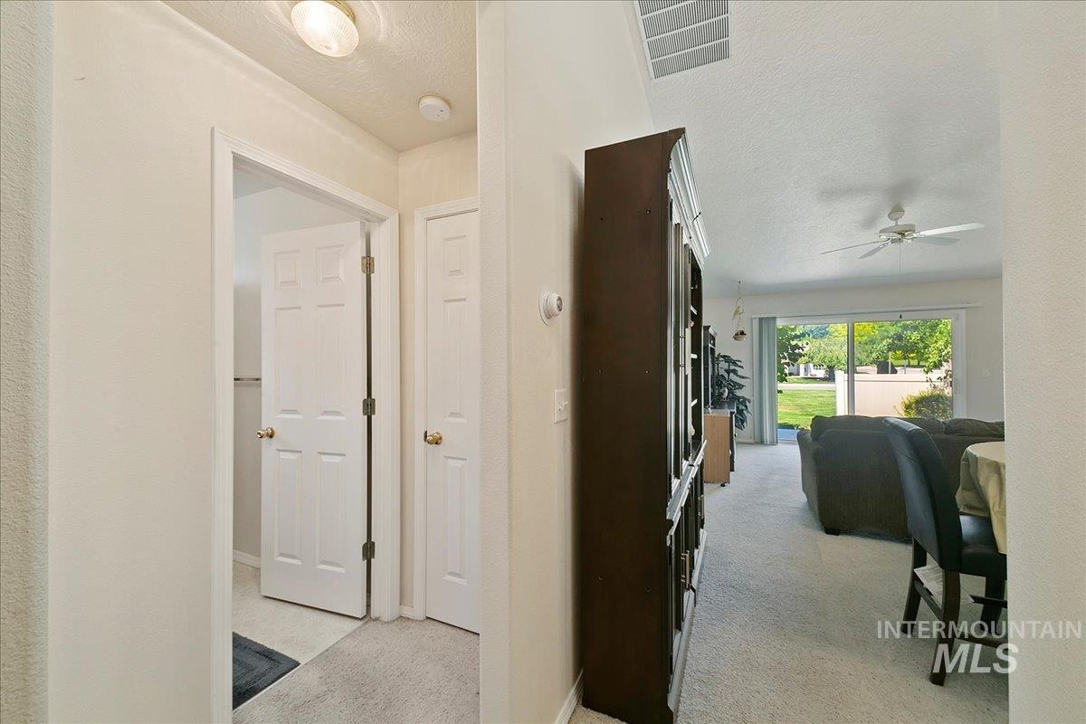 Hall featuring a textured ceiling and light carpet