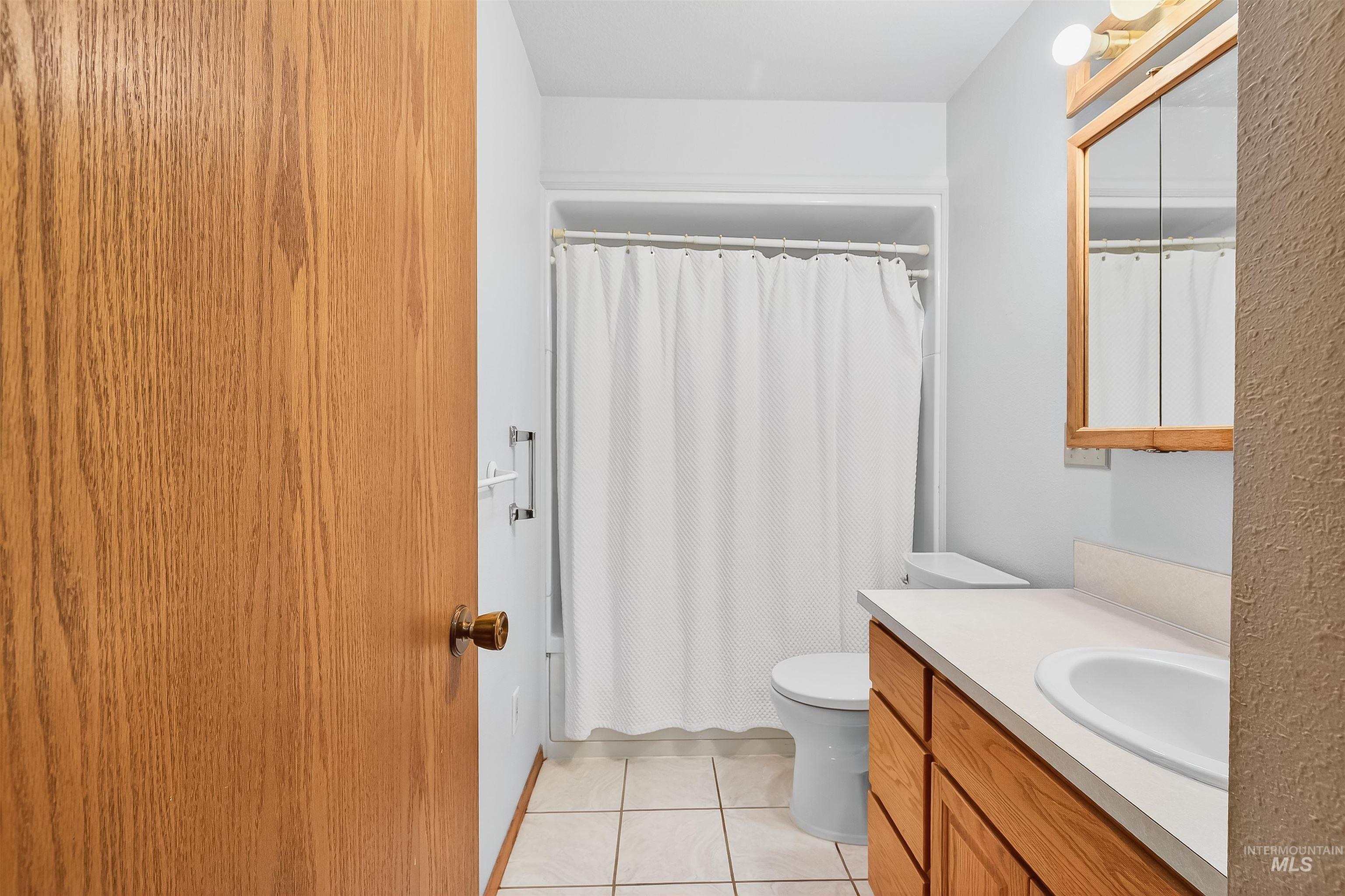 Bathroom with vanity, a shower with shower curtain, and light tile patterned flooring