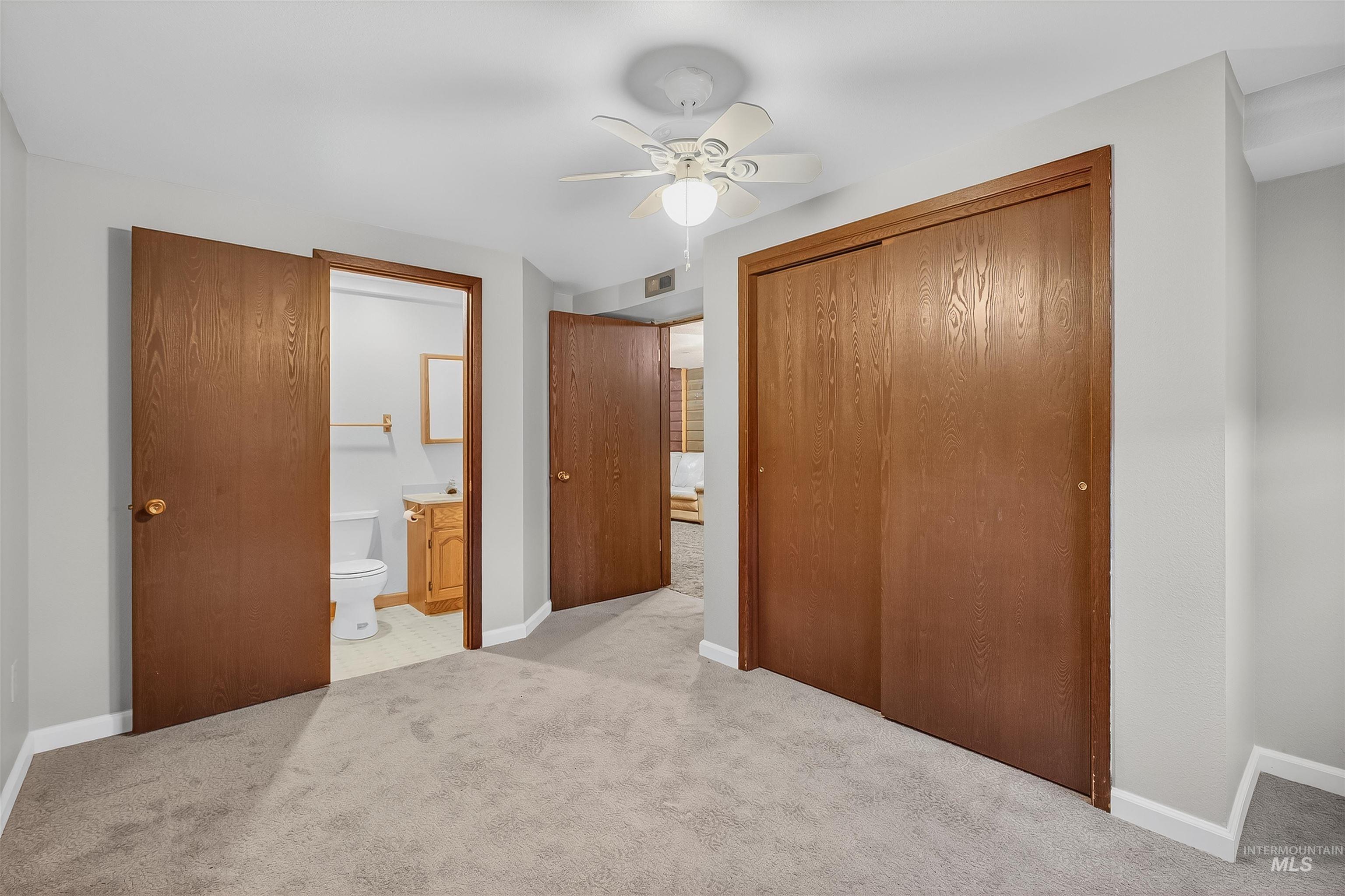 Unfurnished bedroom with light colored carpet, a ceiling fan, ensuite bath, and a closet