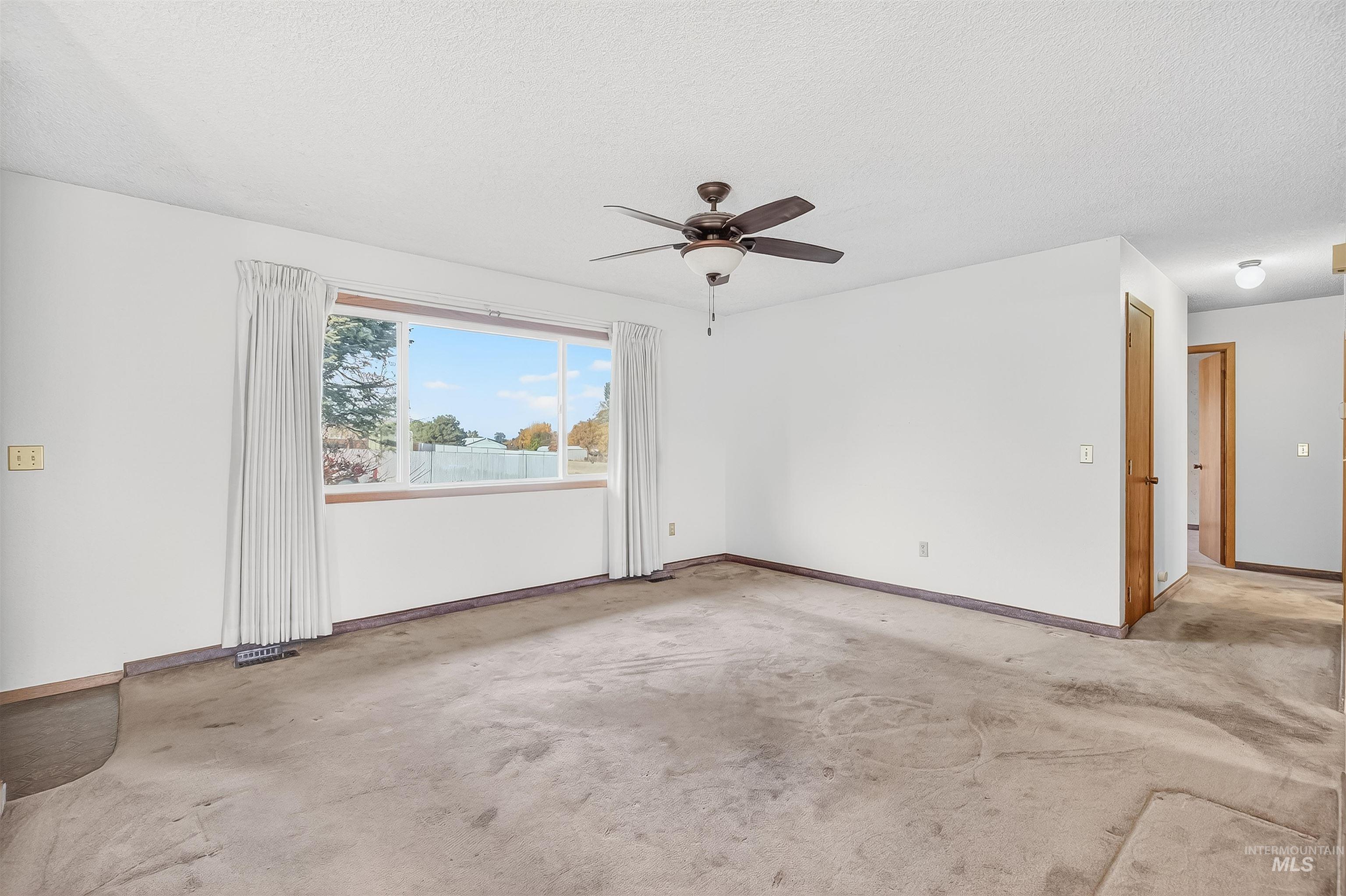 Unfurnished room with light carpet, ceiling fan, and a textured ceiling