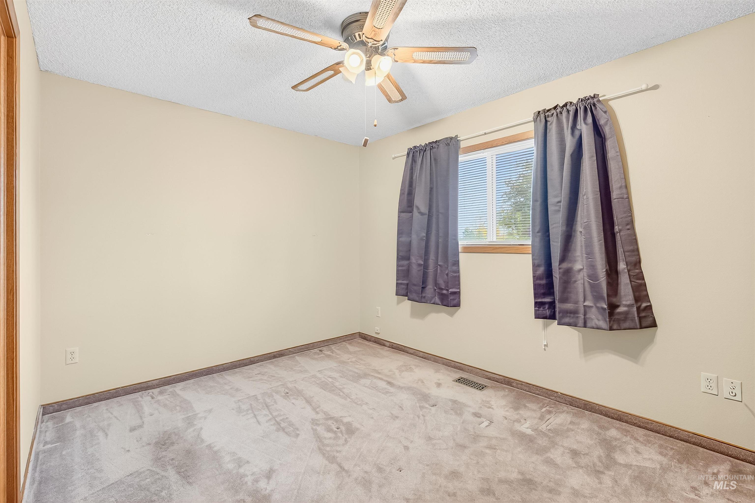Carpeted spare room with a textured ceiling and a ceiling fan