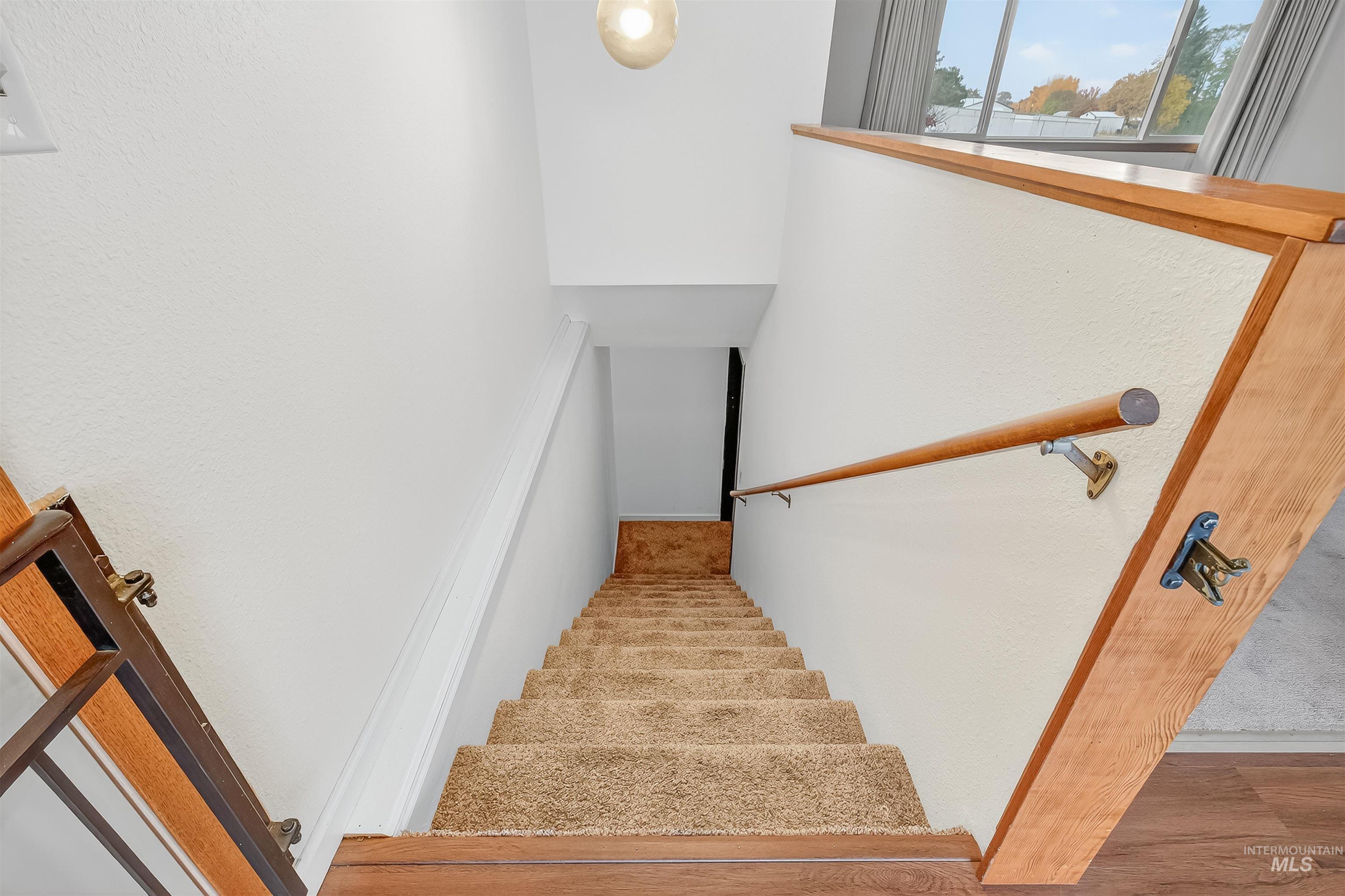 Stairway with wood finished floors and a textured wall