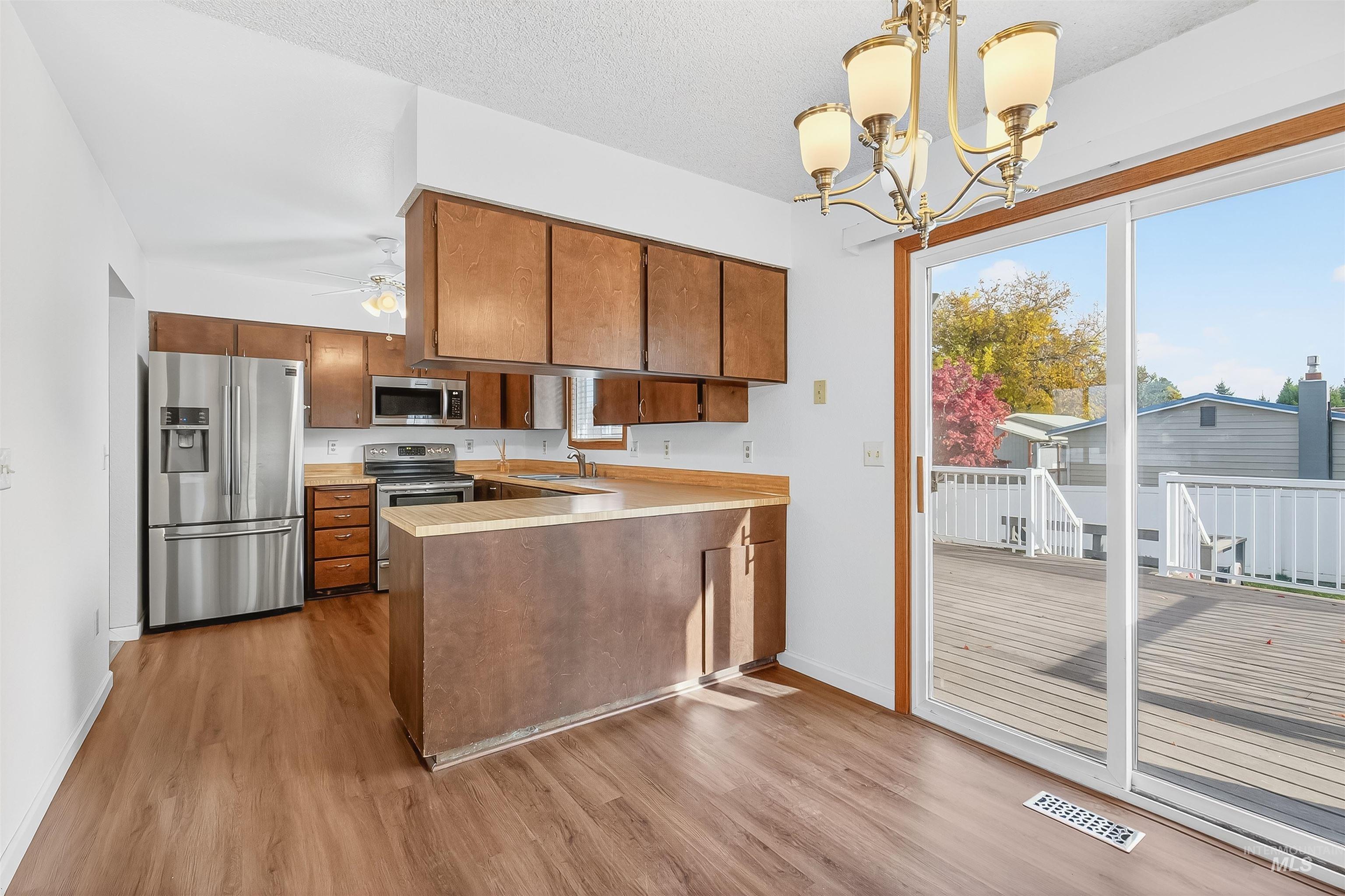 Kitchen featuring light countertops, brown cabinets, pendant lighting, a peninsula, and a textured ceiling