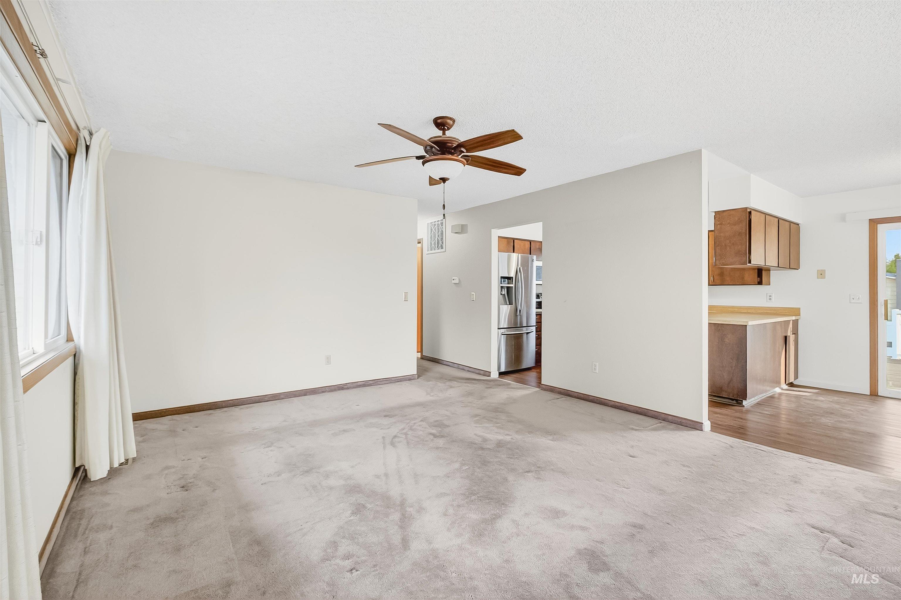 Unfurnished living room featuring light colored carpet and a ceiling fan