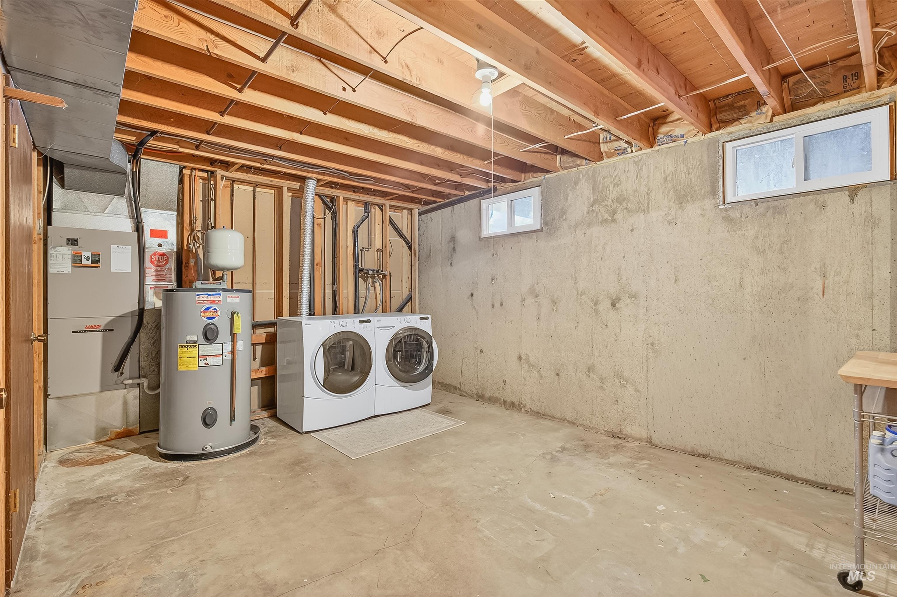 Basement featuring electric water heater, washing machine and dryer, and heating unit