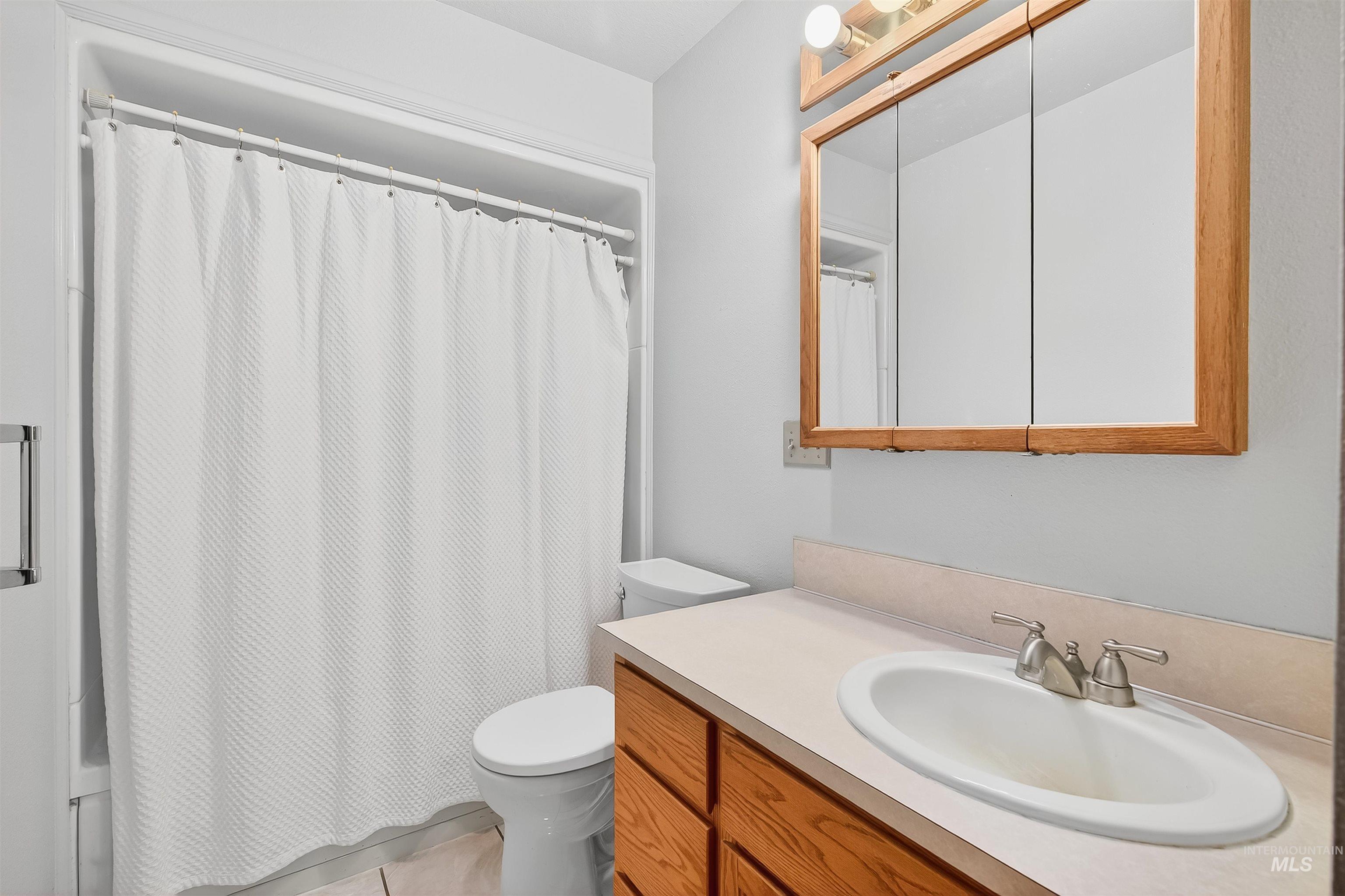 Bathroom featuring vanity, light tile patterned floors, and shower / bath combination with curtain
