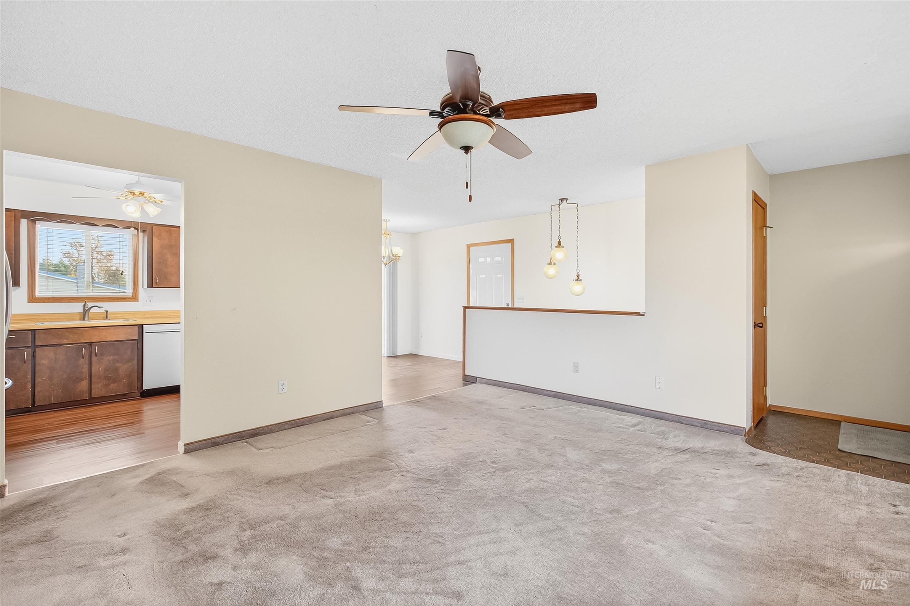 Unfurnished living room featuring ceiling fan and light colored carpet
