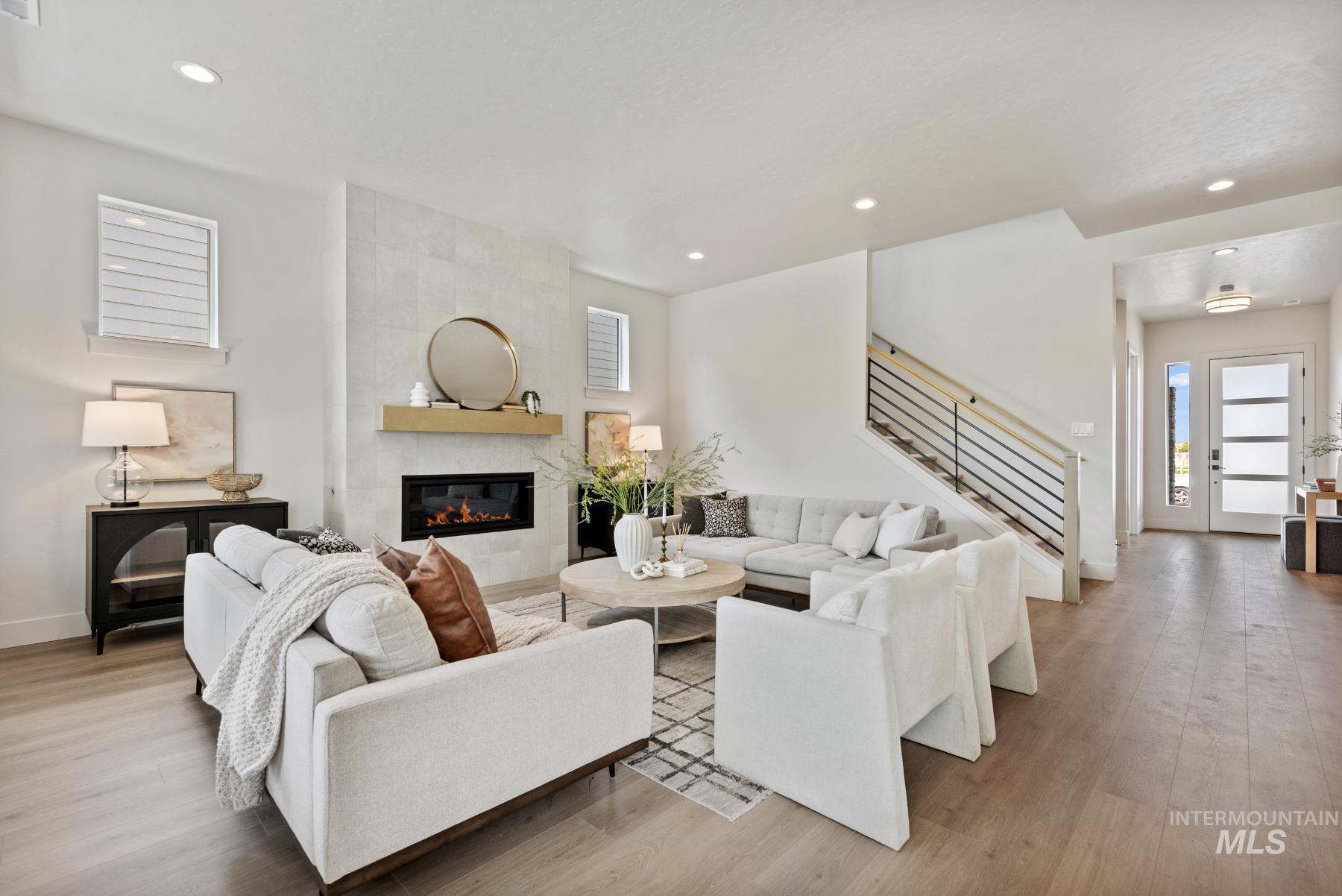 Living room featuring stairway, a tile fireplace, light wood finished floors, and recessed lighting