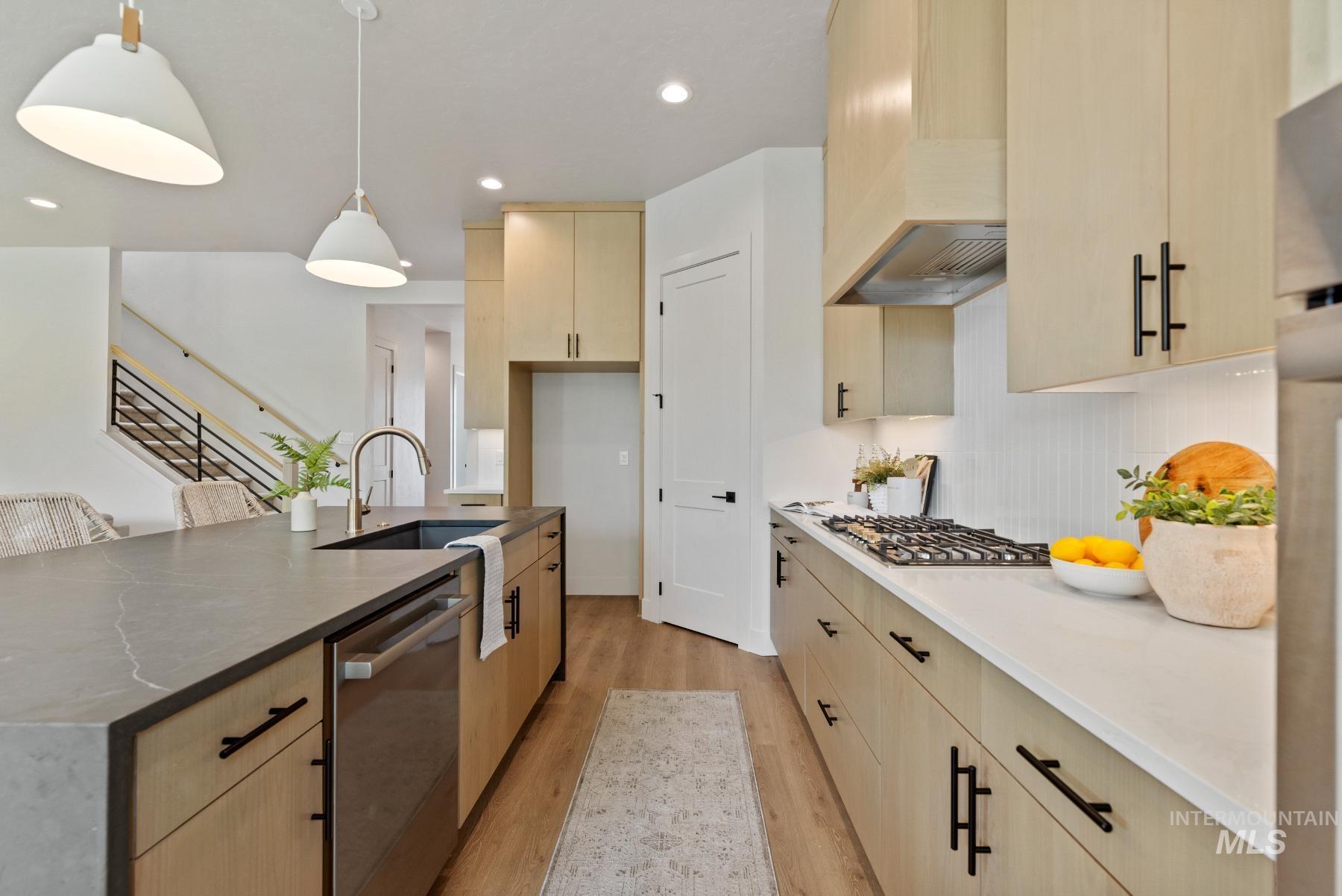 Kitchen featuring light wood-style floors, light brown cabinets, appliances with stainless steel finishes, recessed lighting, and hanging light fixtures