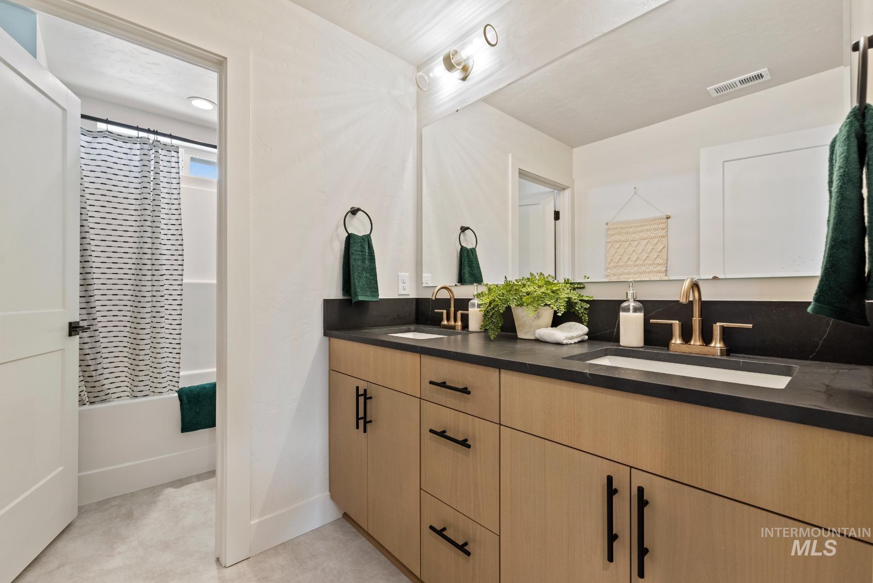 Bathroom with double vanity and shower / bathtub combination with curtain