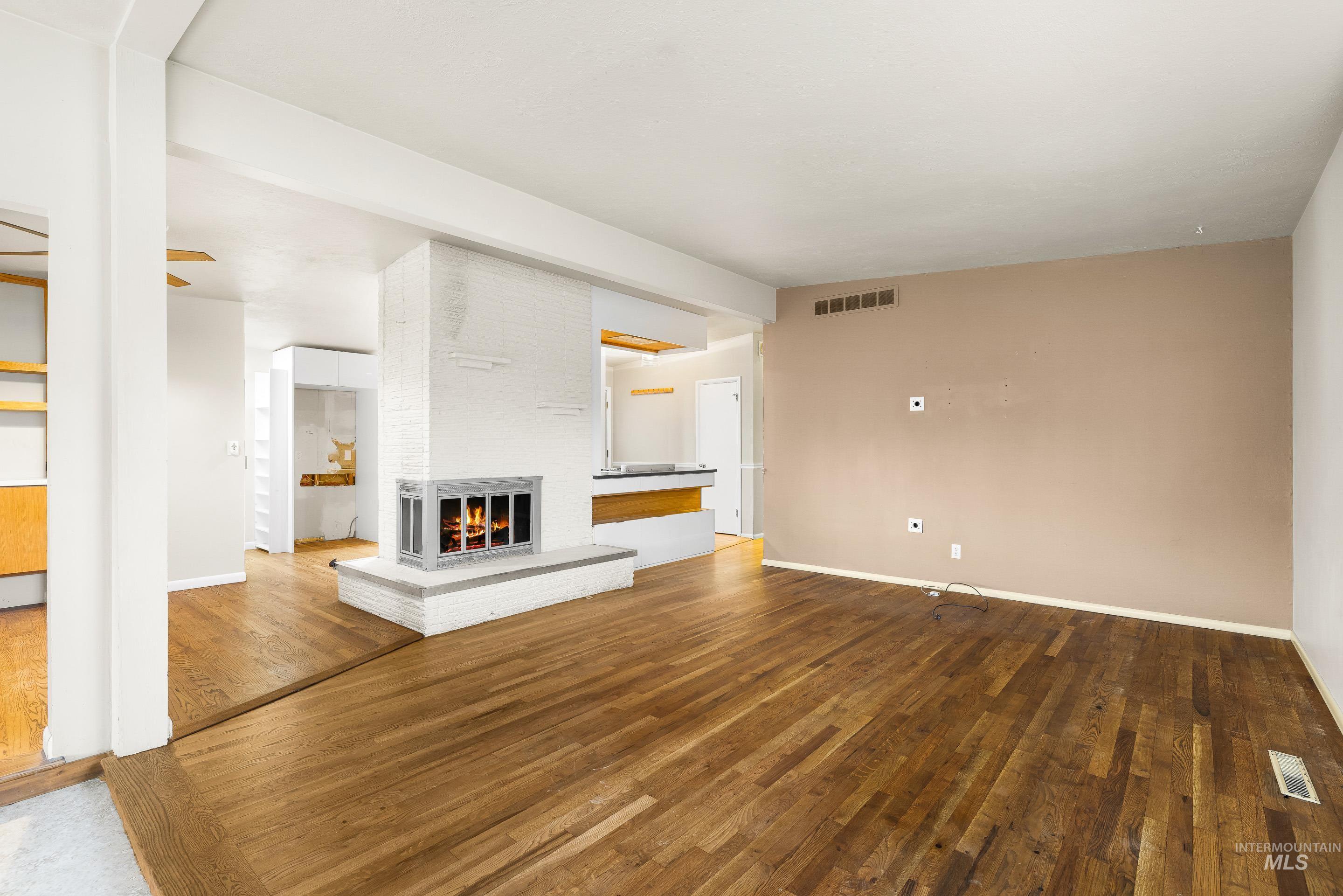 Unfurnished living room with hardwood / wood-style flooring and a brick fireplace