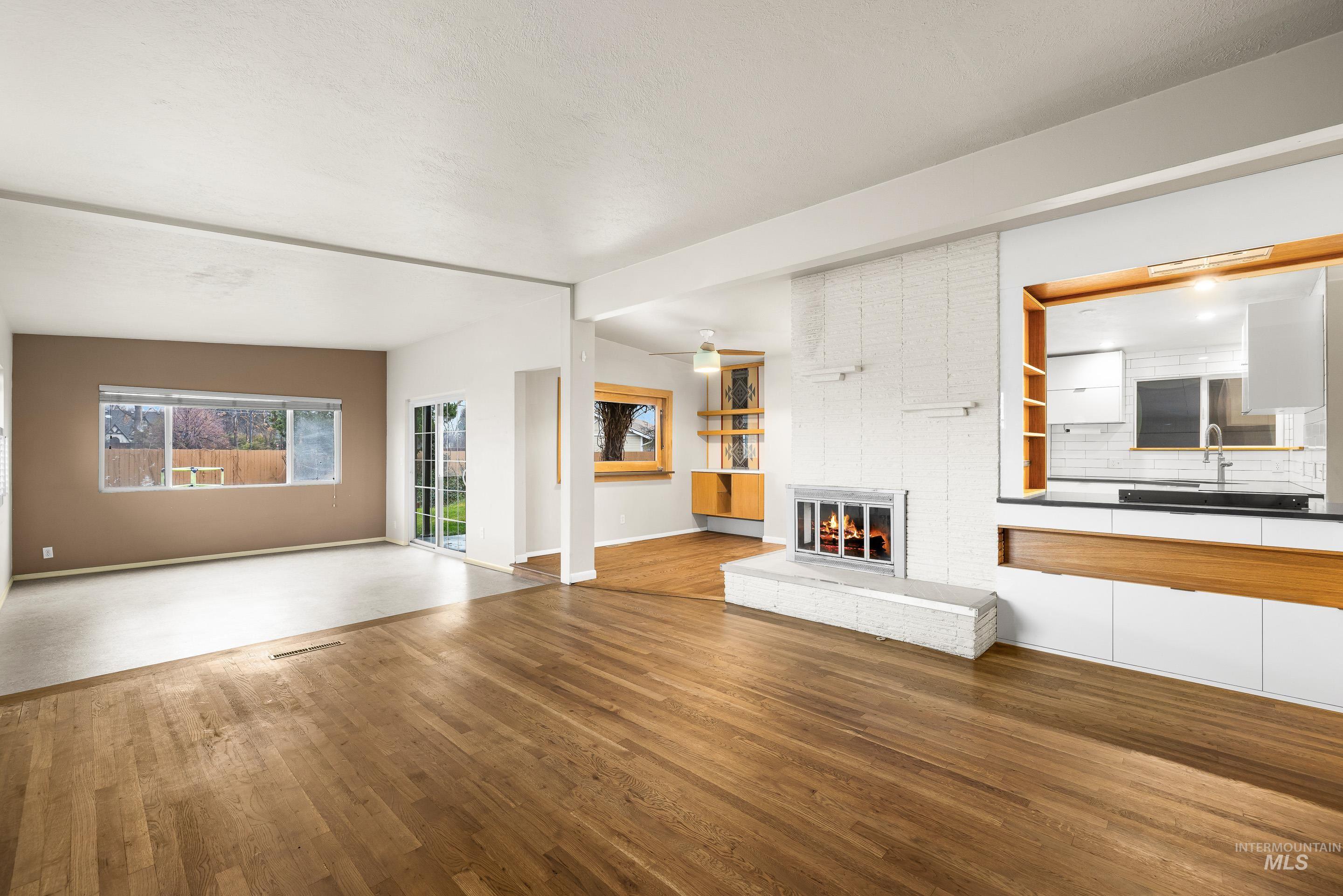Unfurnished living room with a brick fireplace and wood finished floors