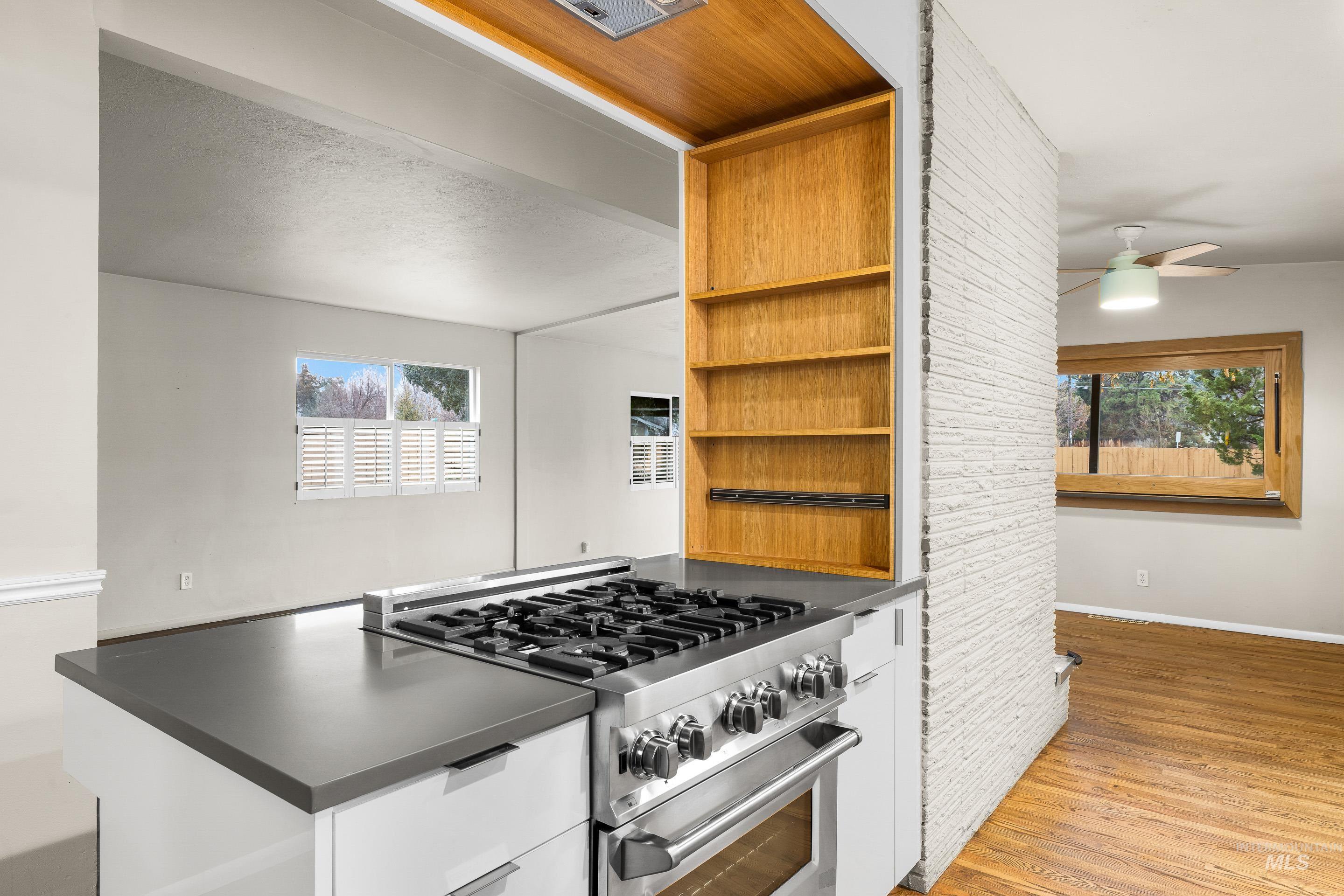 Kitchen featuring high end stove, open shelves, dark countertops, and plenty of natural light